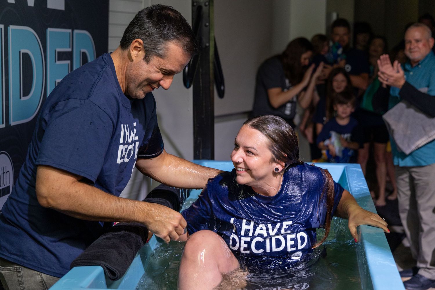 Two people share joyful moment during indoor baptism ceremony. Portrava Creative Studios