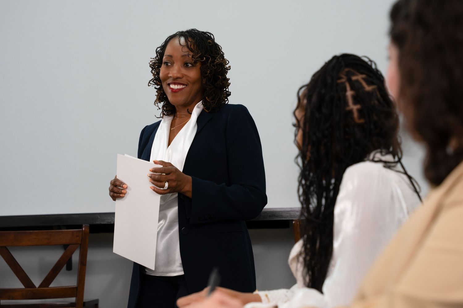 Professional woman presenting to colleagues in business meeting room setting. Portrava Creative Studios