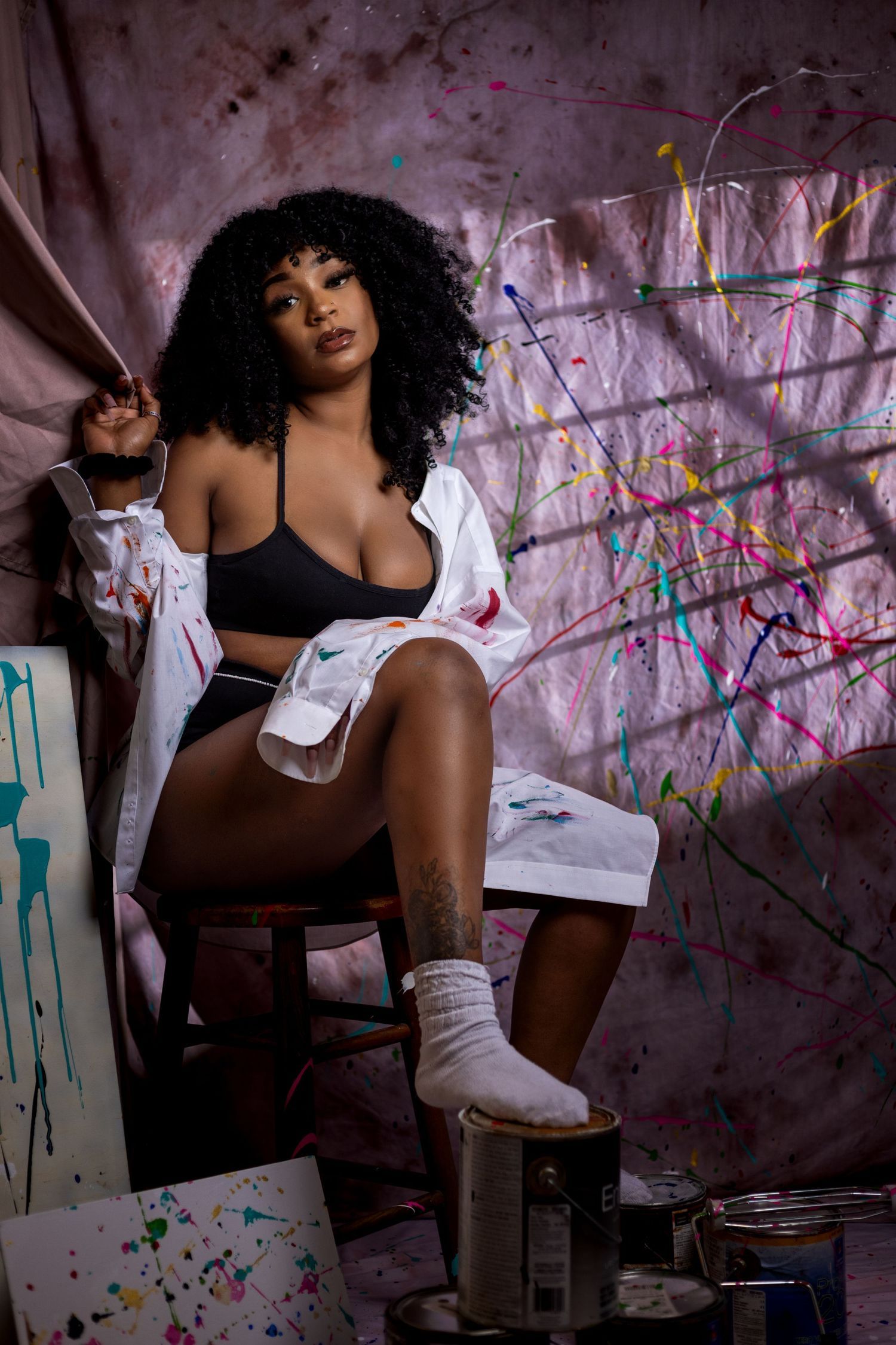 Artistic boudoir photo with a paint splattered white wall backdrop. Portrava Creative Studios