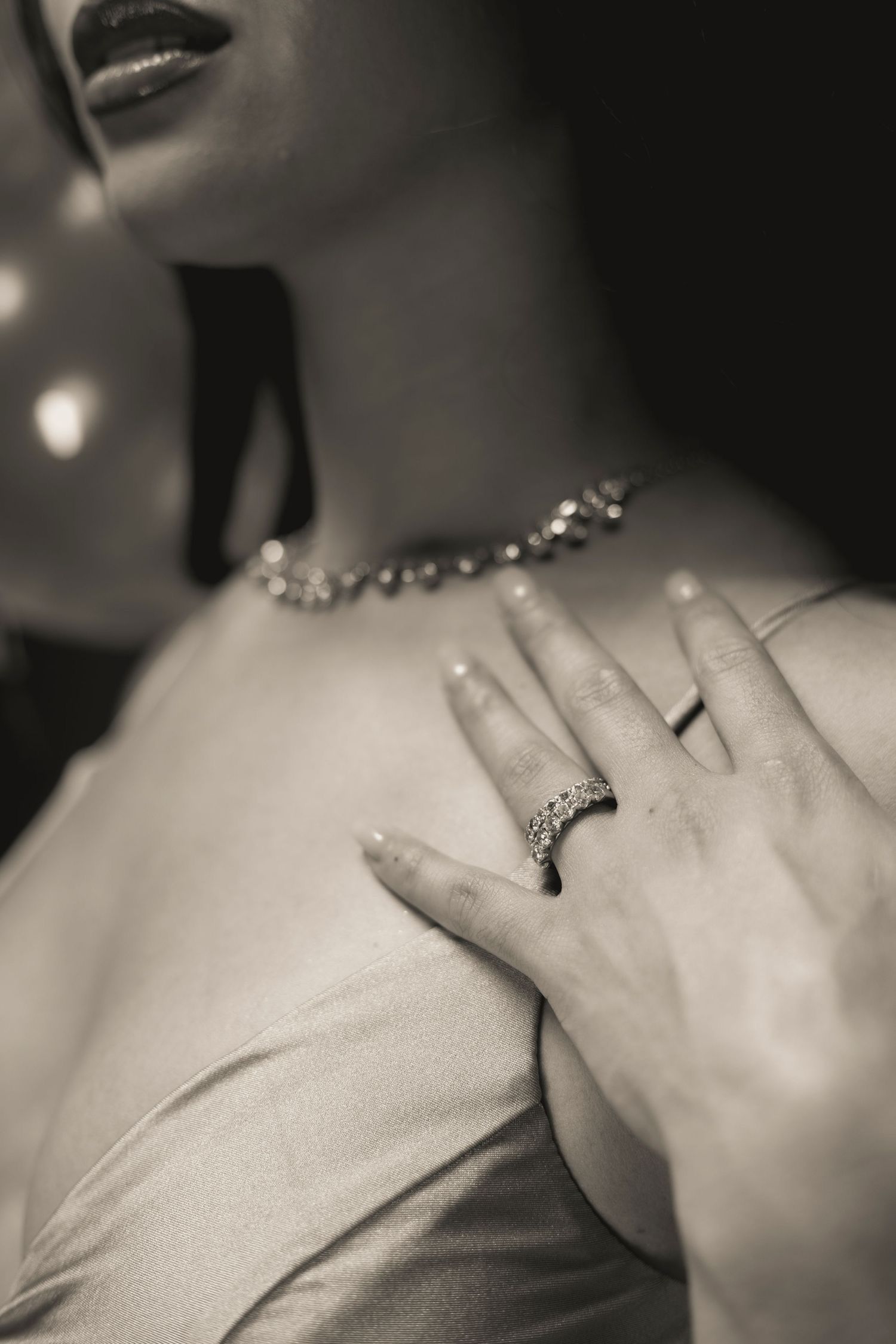 Close-up of hand wearing jewelry and sparkly necklace against light colored fabric. Portrava Creative Studios
