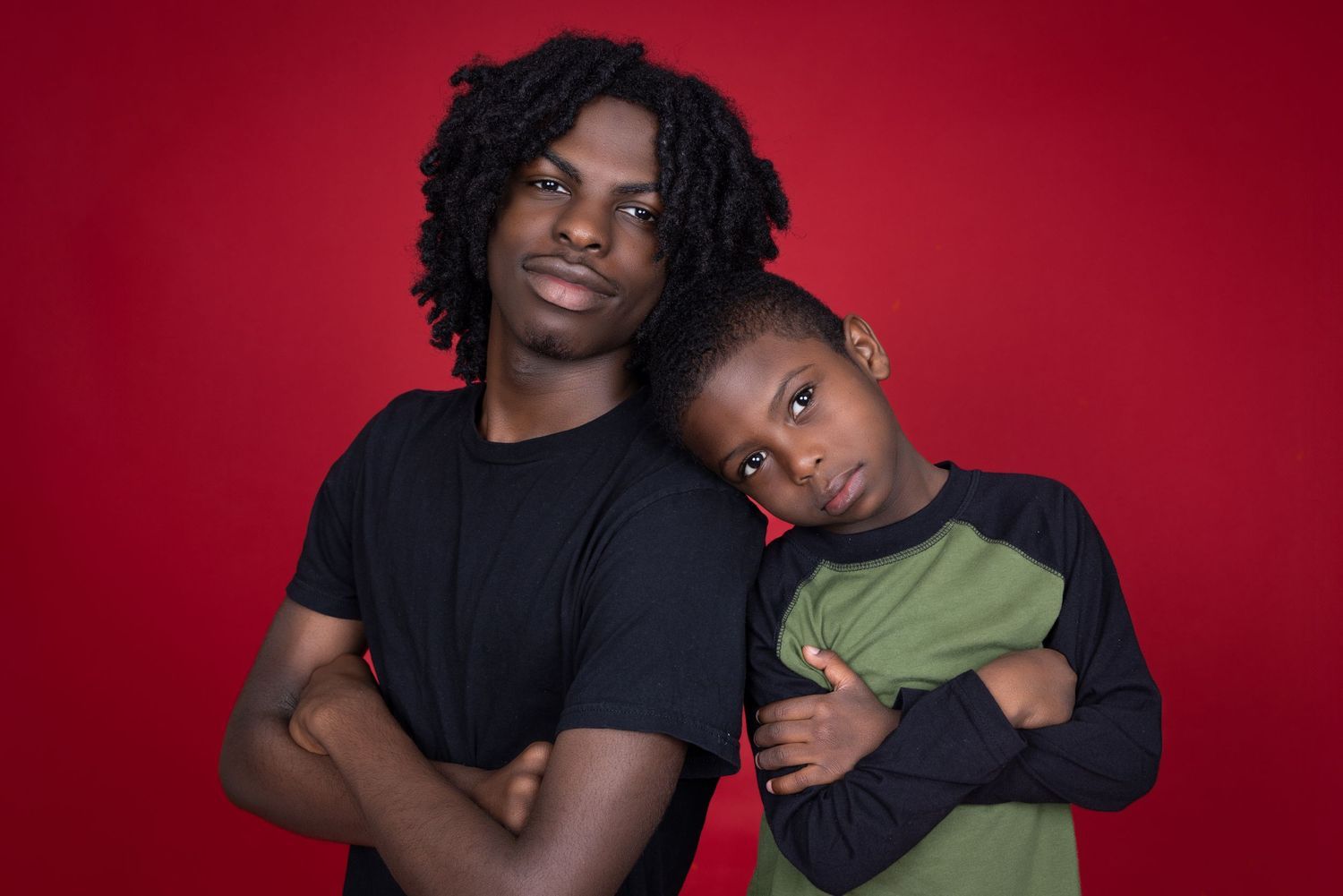 Heartwarming portrait of parent and child against red background. Portrava Creative Studios