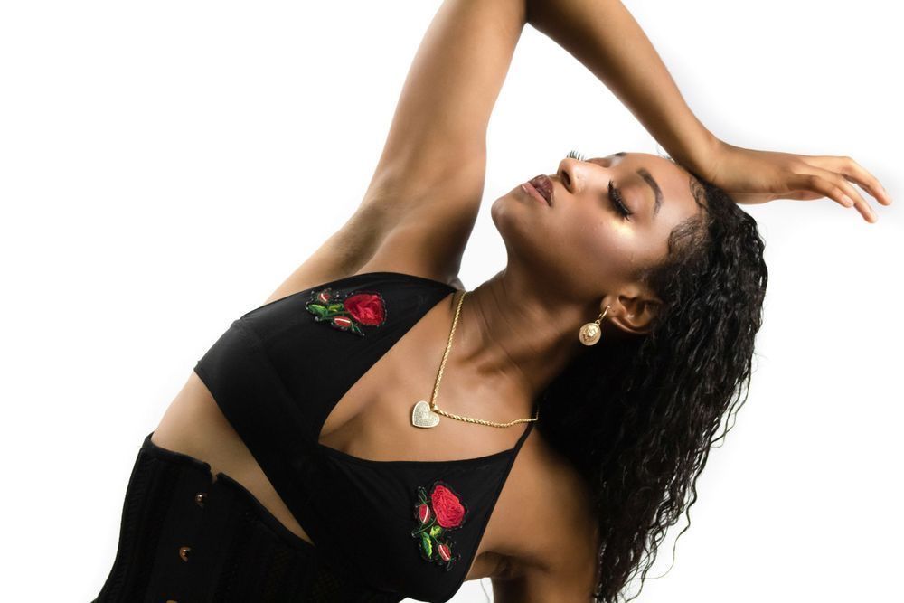 Dramatic dance pose against white background wearing black outfit with rose details. Portrava Creative Studios