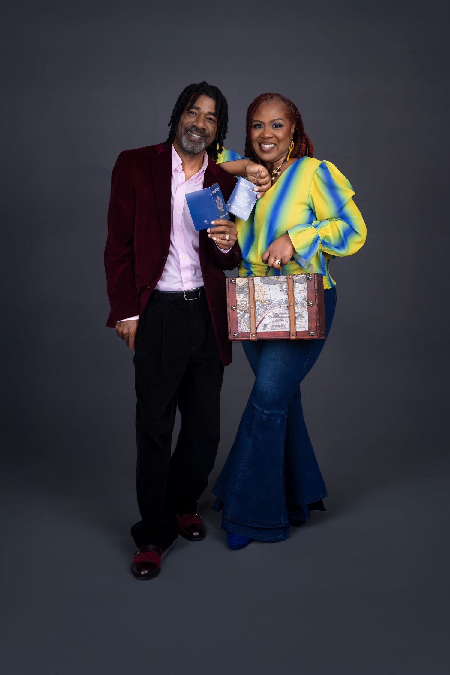 Studio portrait of stylishly dressed couple posing with decorative box against dark background. Portrava Creative Studios