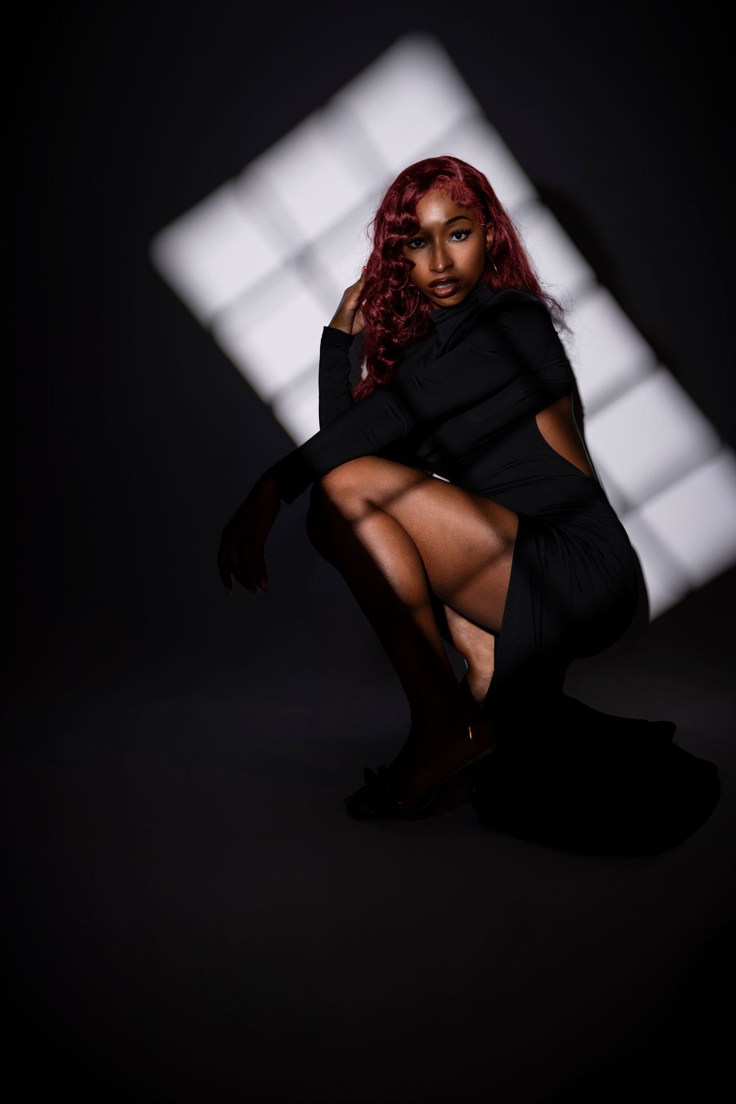 Artistic studio portrait with dramatic lighting and geometric white backdrop. Portrava Creative Studios