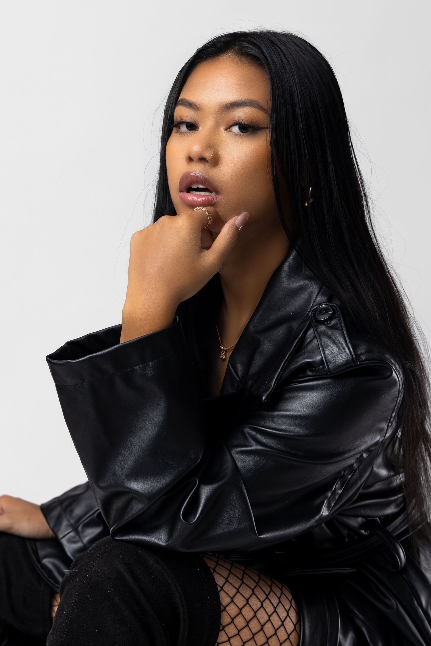 Fashion portrait featuring sleek black leather jacket and long straight hair against white background. Portrava Creative Studios