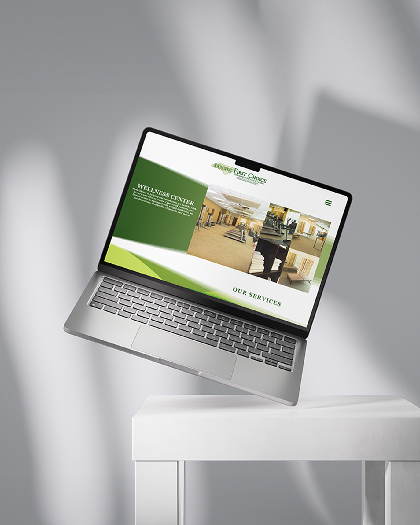 Laptop displaying a green and white website design with office interior mockup on a white table. Portrava Creative Studios