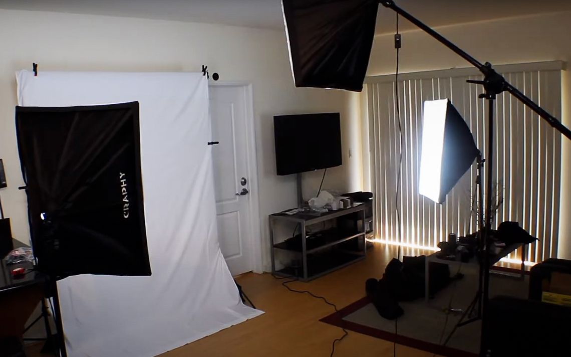 Portrava CS Professional photography studio setup with white backdrop, softboxes, and lighting equipment in a home environment. Portrava