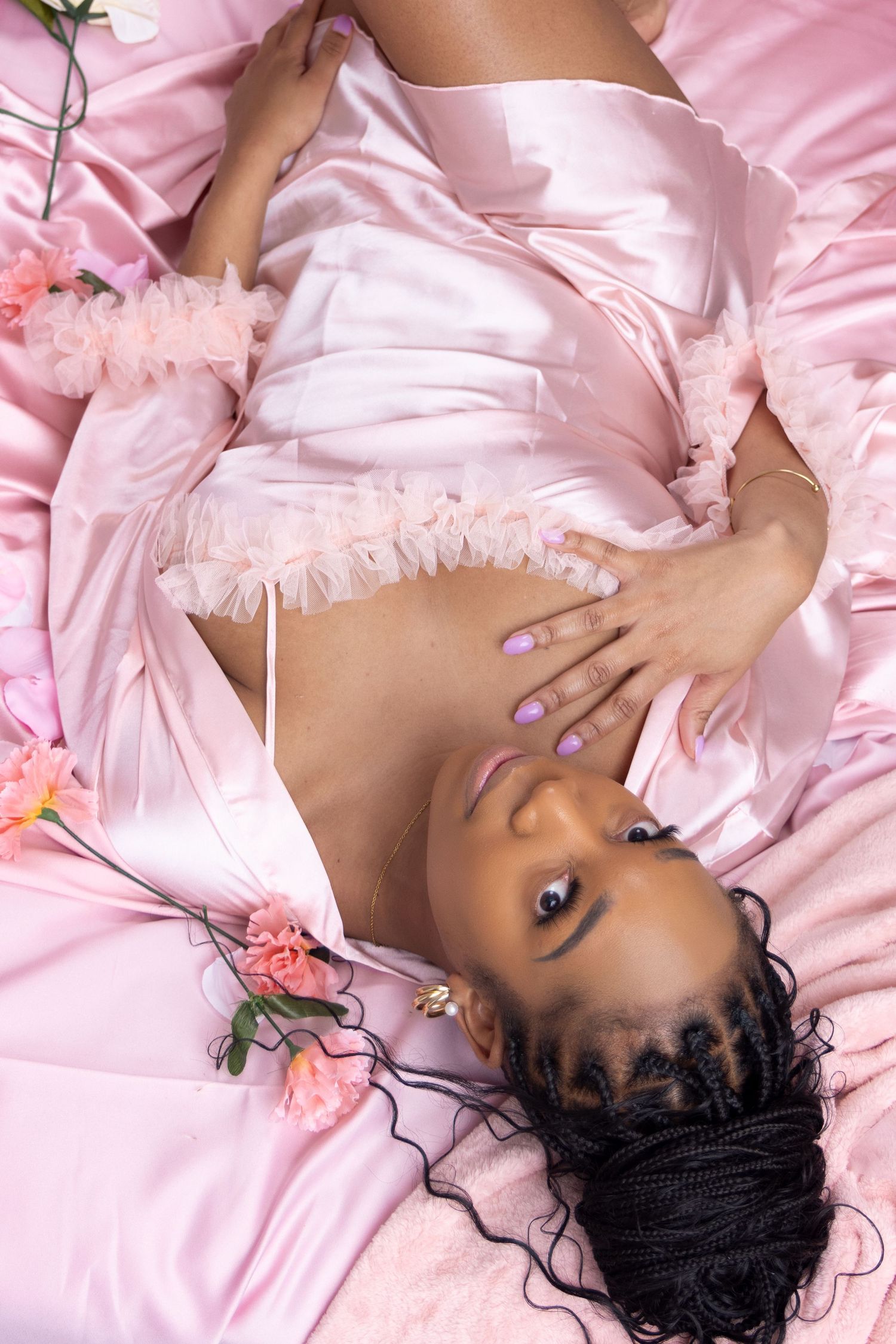 Artistic boudoir photography with pink satin and floral elements. Portrava Creative Studios