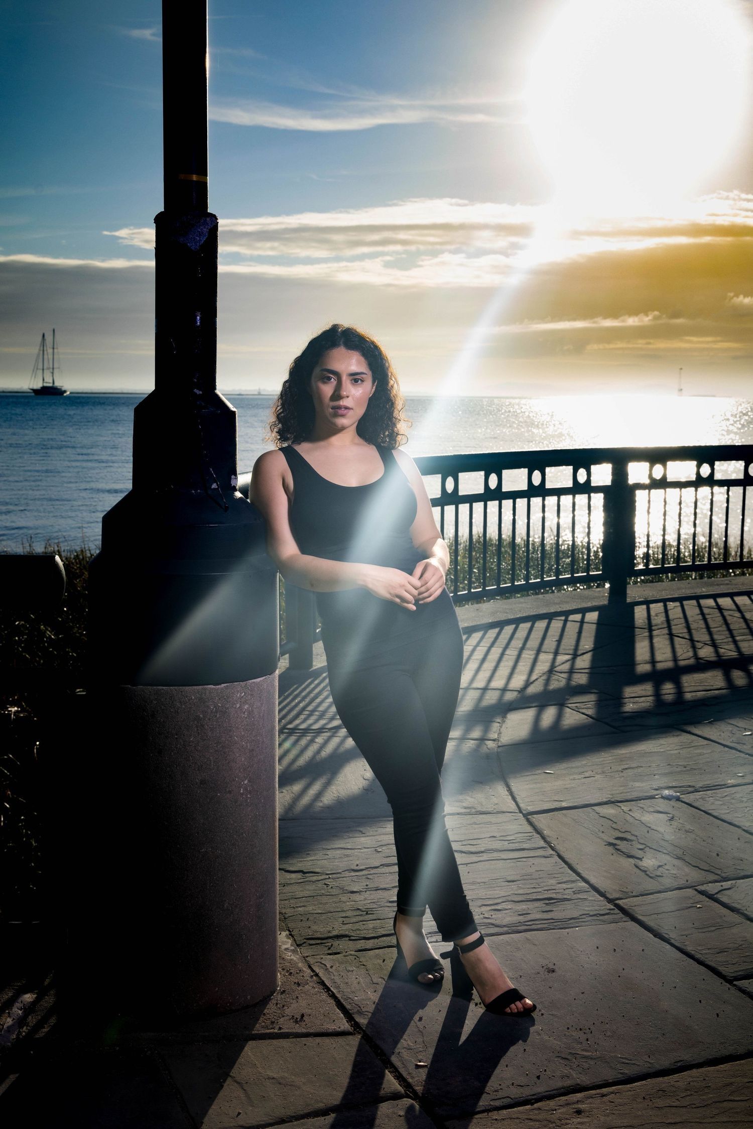 Sunset portrait by waterfront with silhouette against pier and boats in background. Portrava Creative Studios