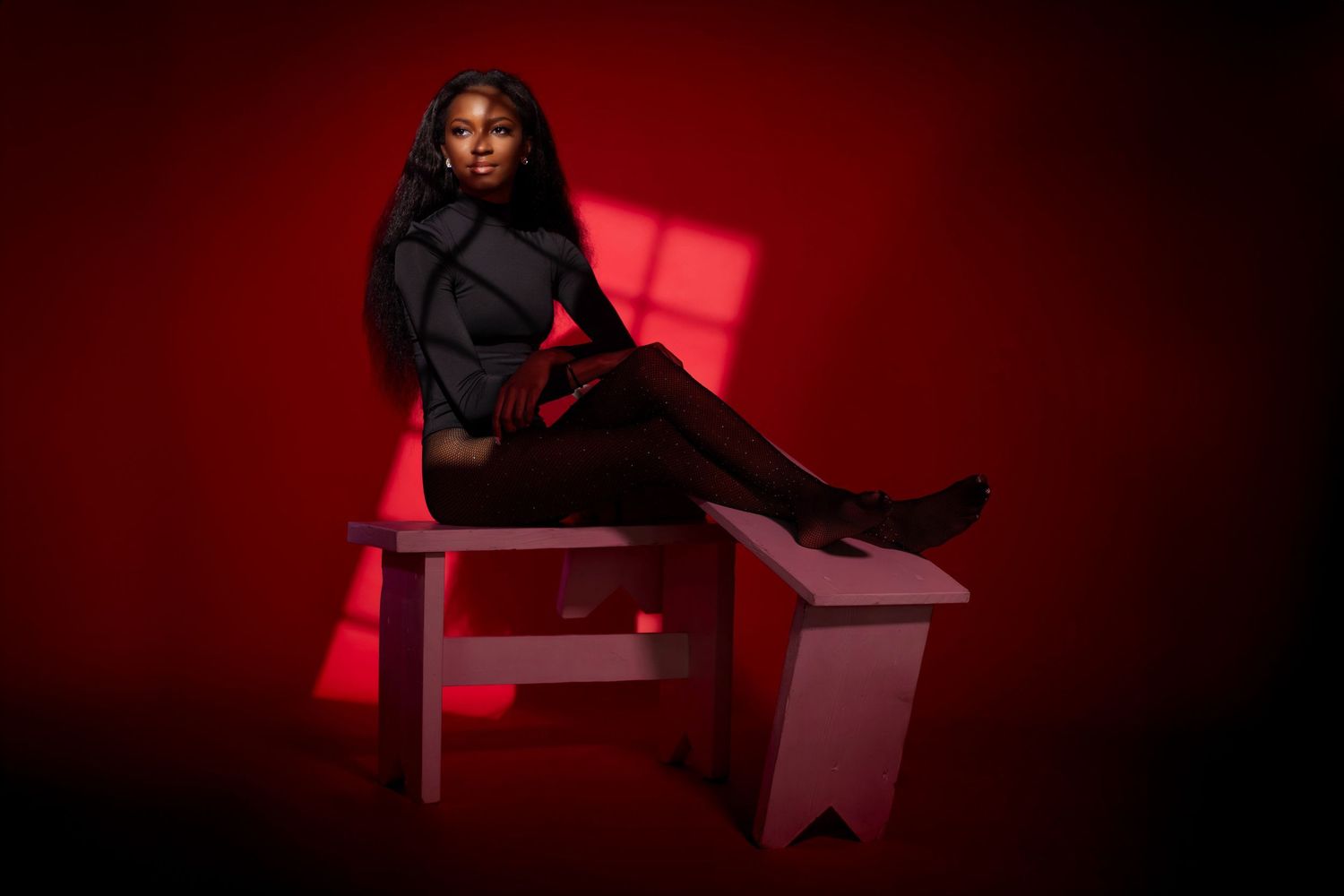 Moody fashion portrait in red lighting on geometric furniture. Portrava Creative Studios
