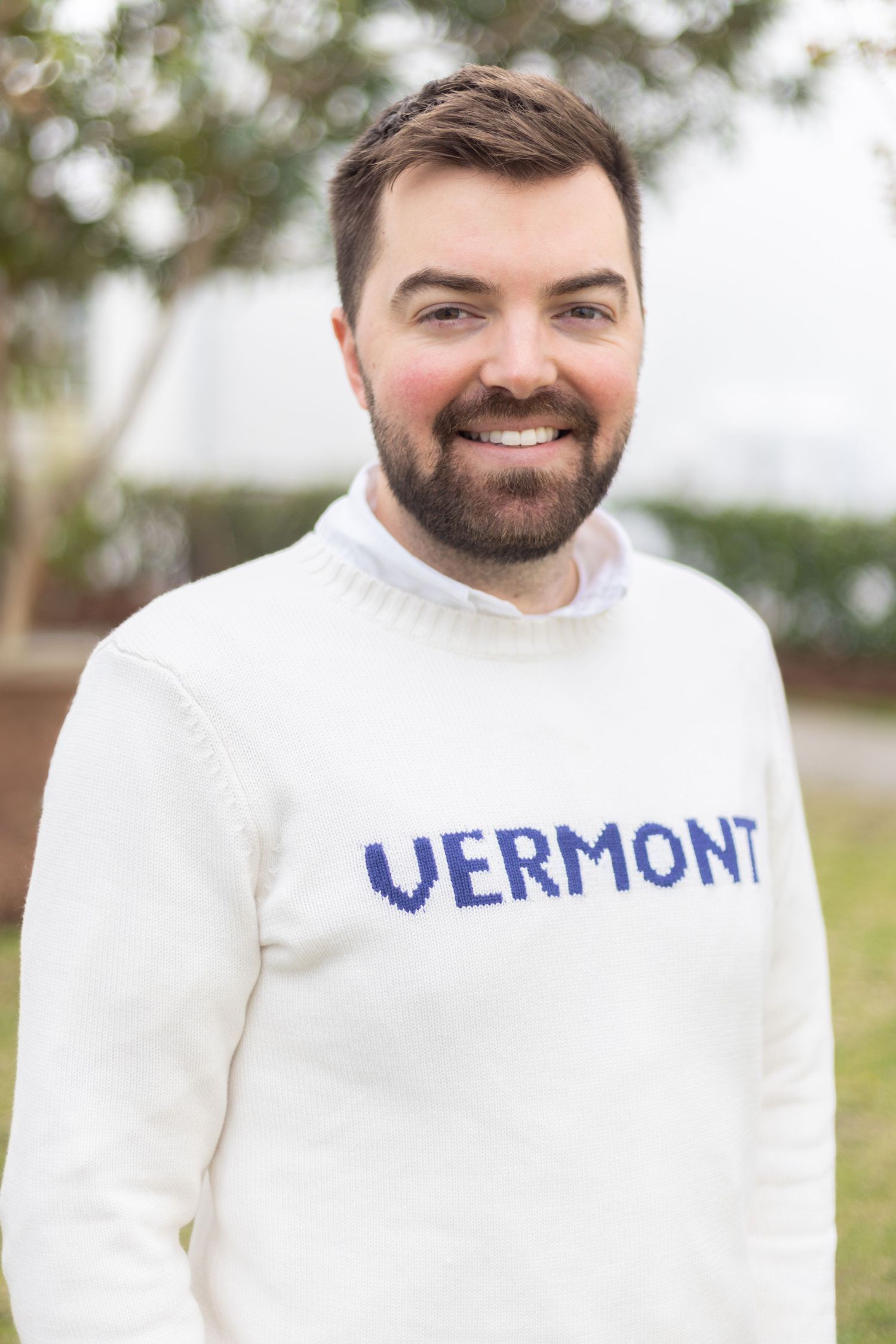 Smiling person wearing white Vermont sweater in outdoor setting. Portrava Creative Studios