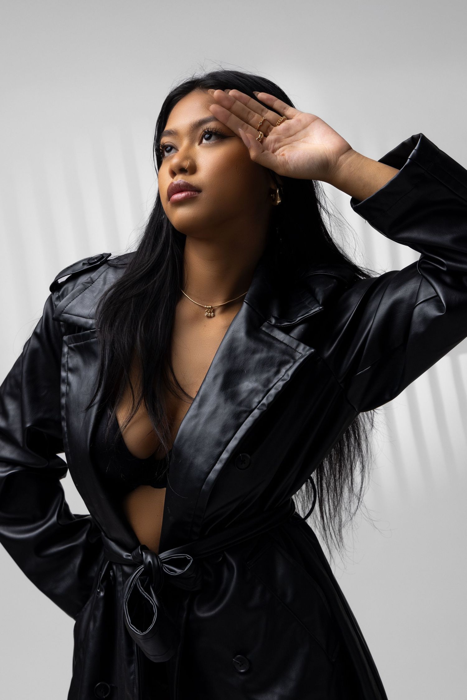Fashion portrait with black leather jacket and dramatic hand gesture against grey backdrop. Portrava Creative Studios