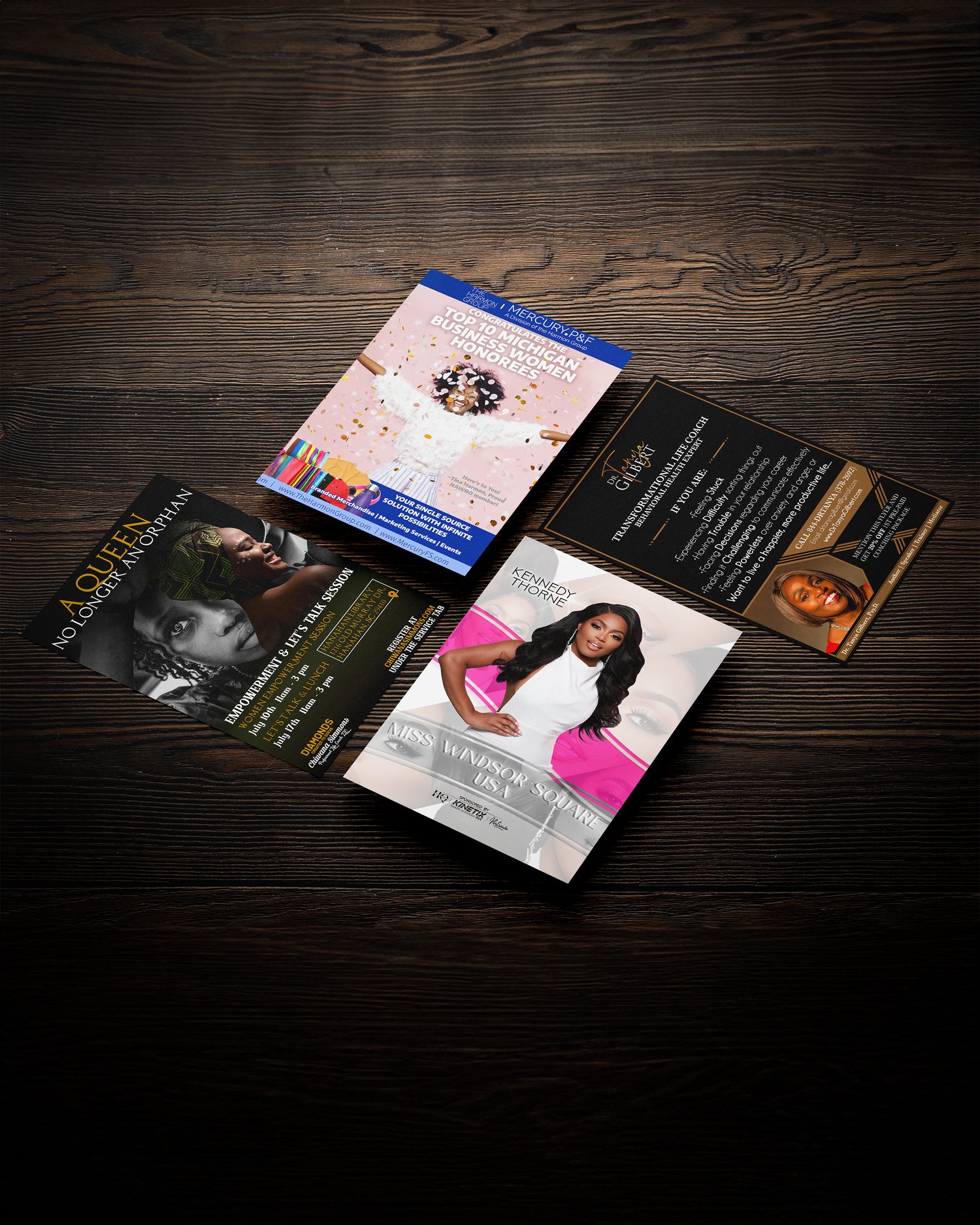 Collection of album covers and design layouts displayed on dark wooden surface. Portrava Creative Studios