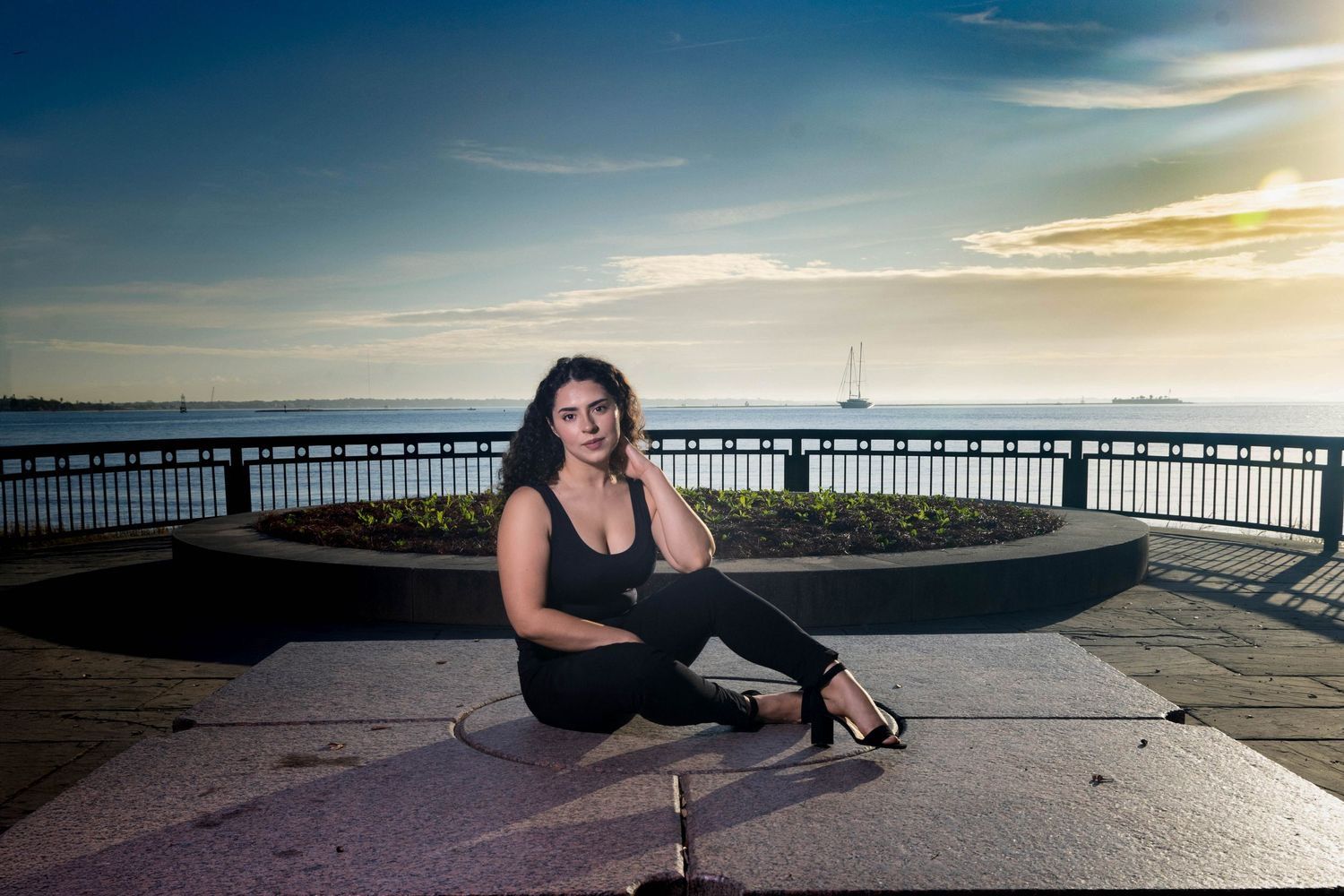 Outdoor portrait at sunset on waterfront walkway with dramatic sky and railing. Portrava Creative Studios