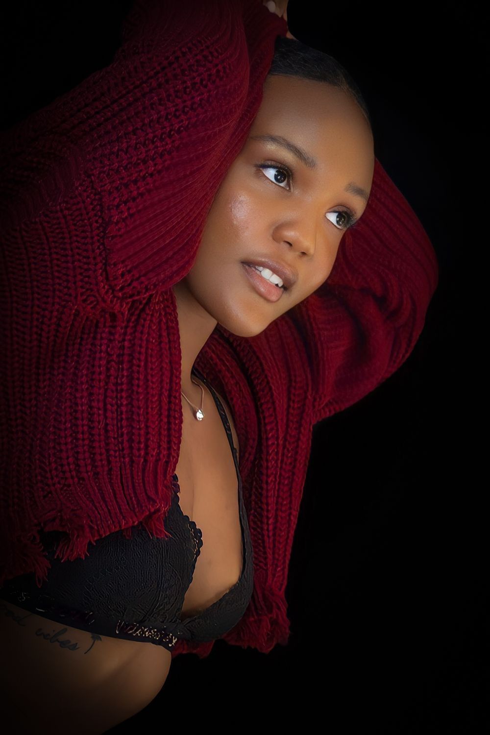 Artistic portrait featuring burgundy sweater against dark background. Portrava Creative Studios