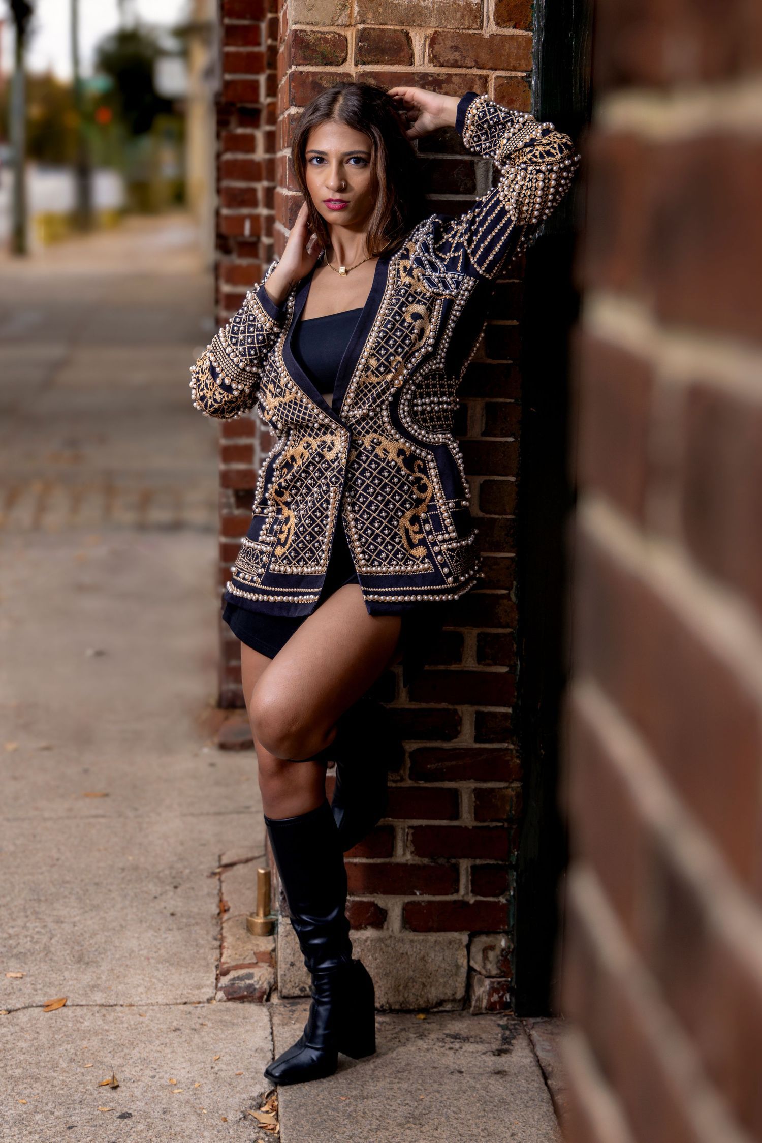 Urban fashion portrait with model in patterned cardigan against brick wall. Portrava Creative Studios