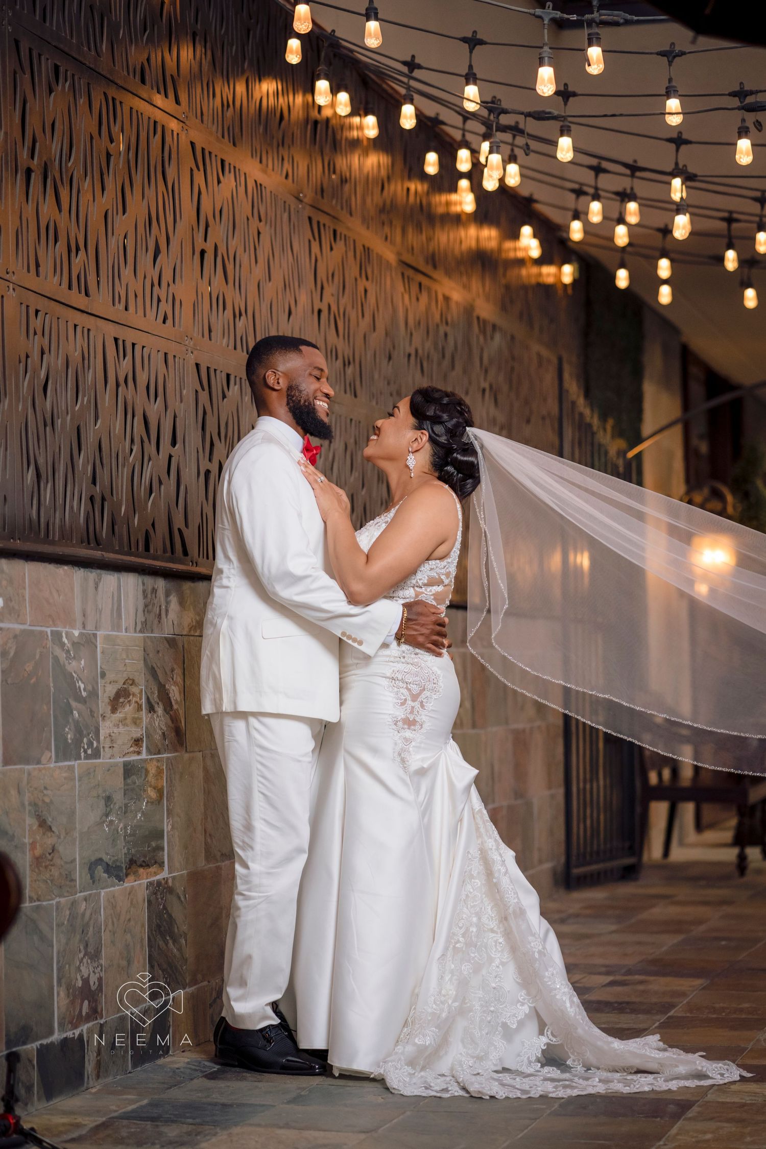 A romantic wedding moment captured under string lights with elegant decor.