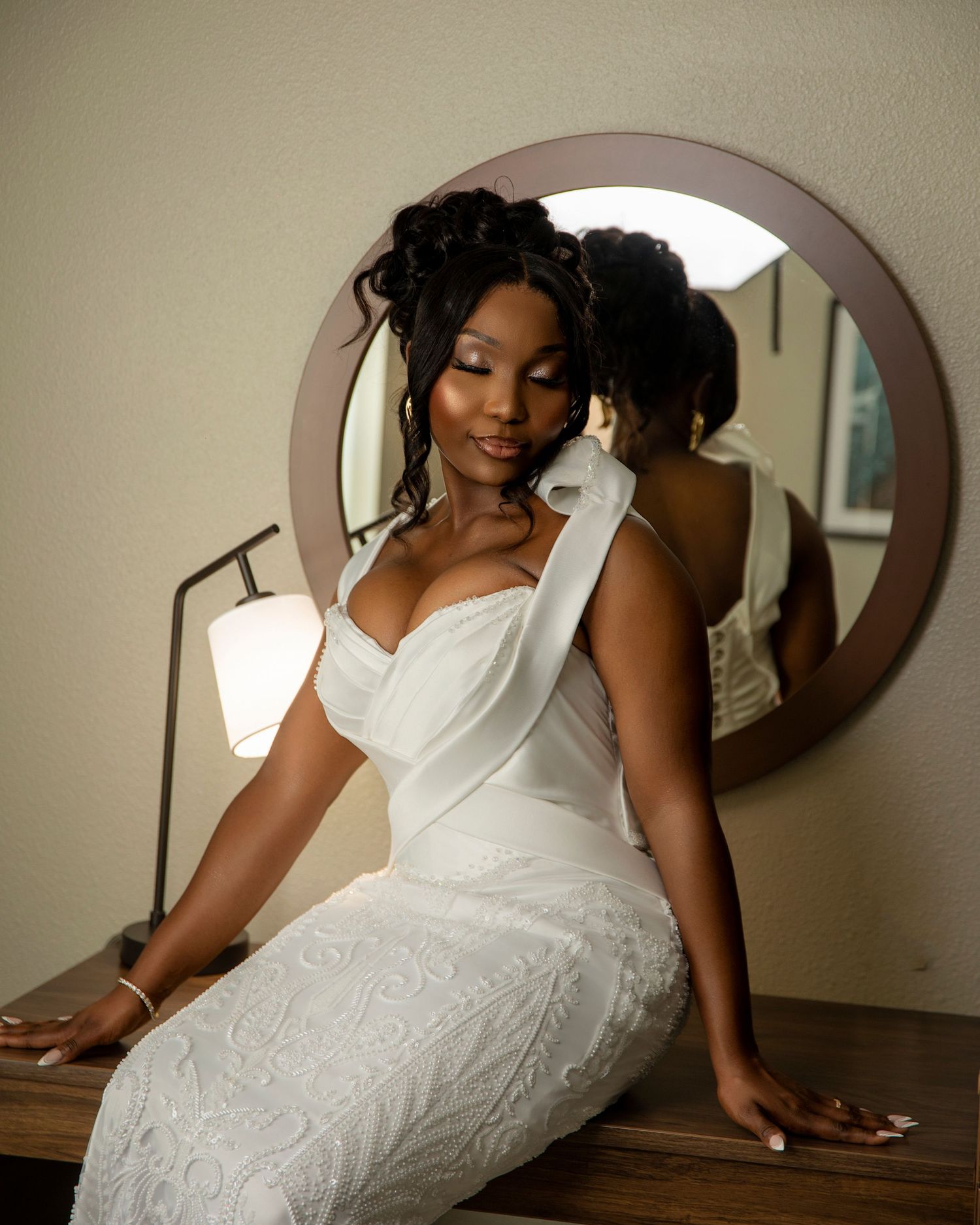 Stunning bridal portrait reflected in circular mirror showing intricate white lace gown.