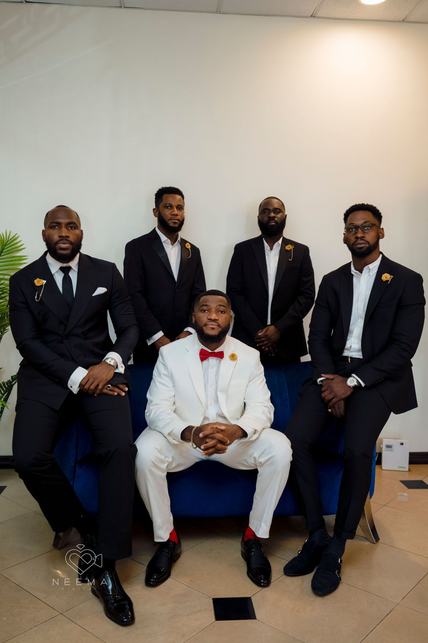 A wedding party photo featuring groomsmen in black suits with a groom in white.