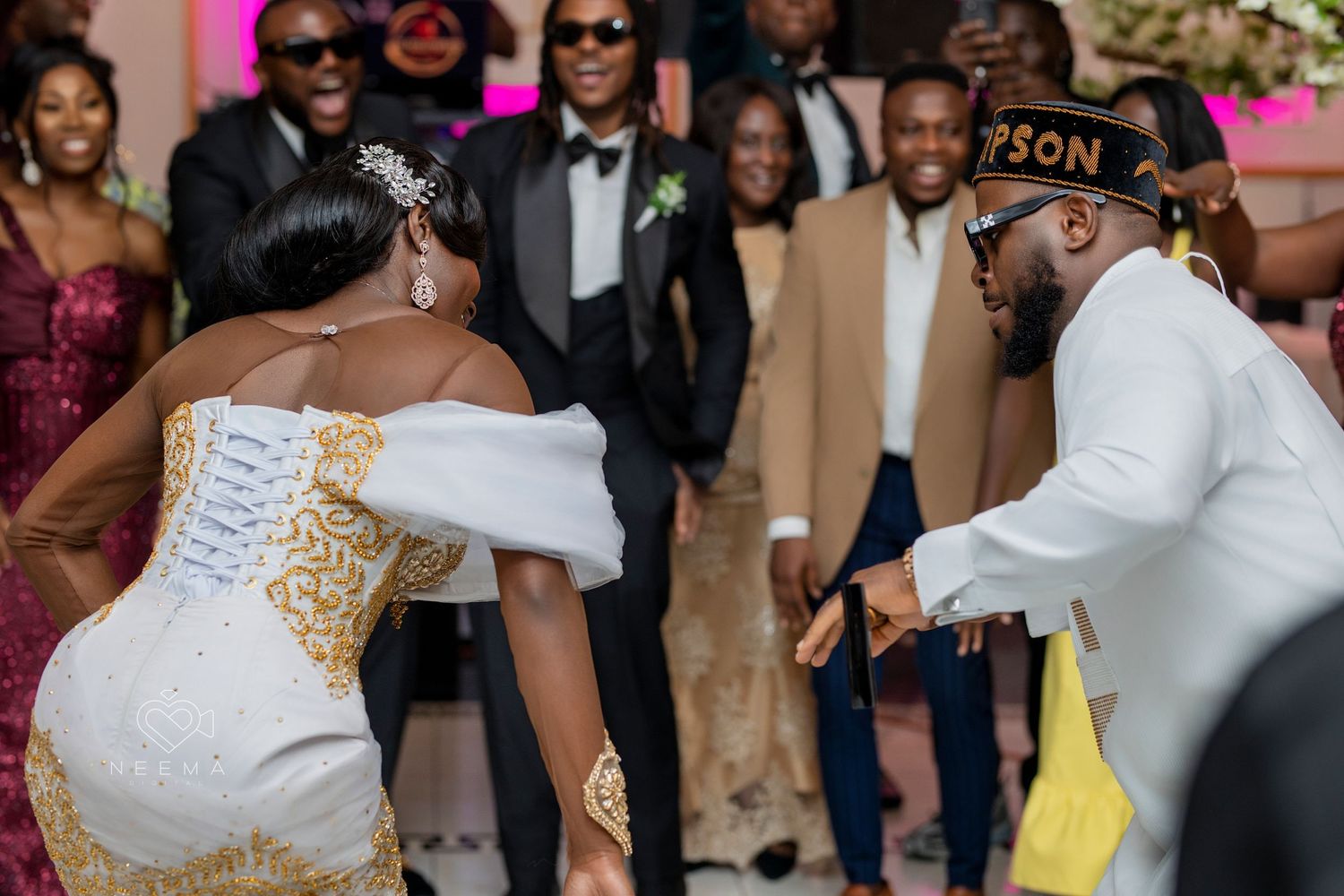 Wedding celebration with guests dancing in formal attire at an indoor venue.