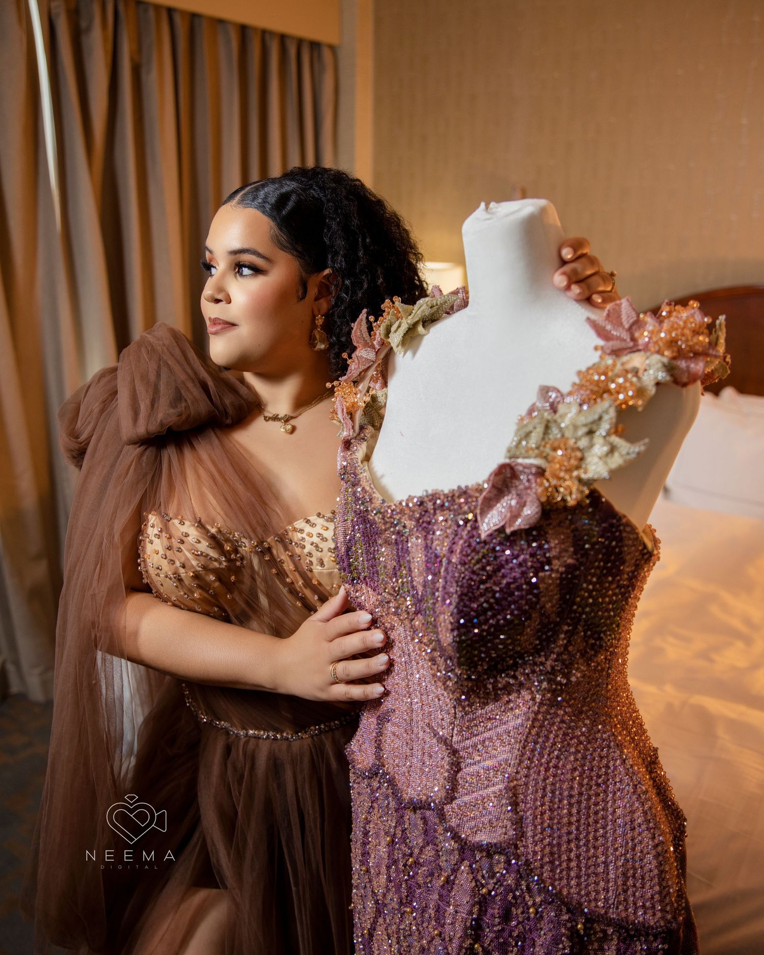 Person in brown gown poses next to purple beaded dress on mannequin.