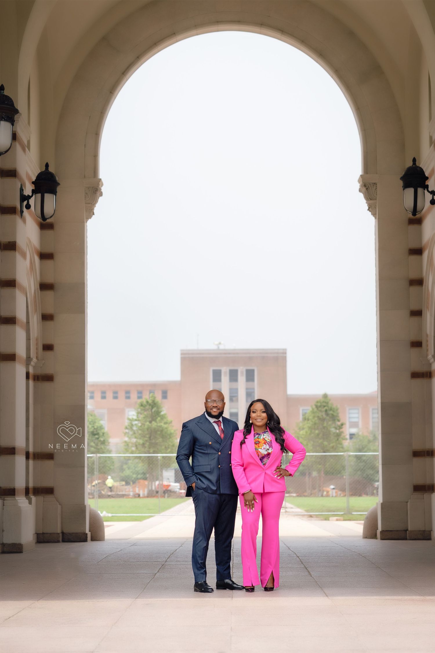 Couple in formal attire standing under grand archway entrance.