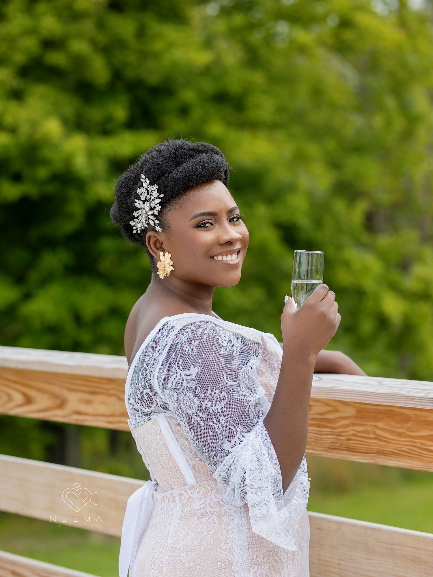 Bride in lace dress with crystal hair accessory enjoying champagne on deck.