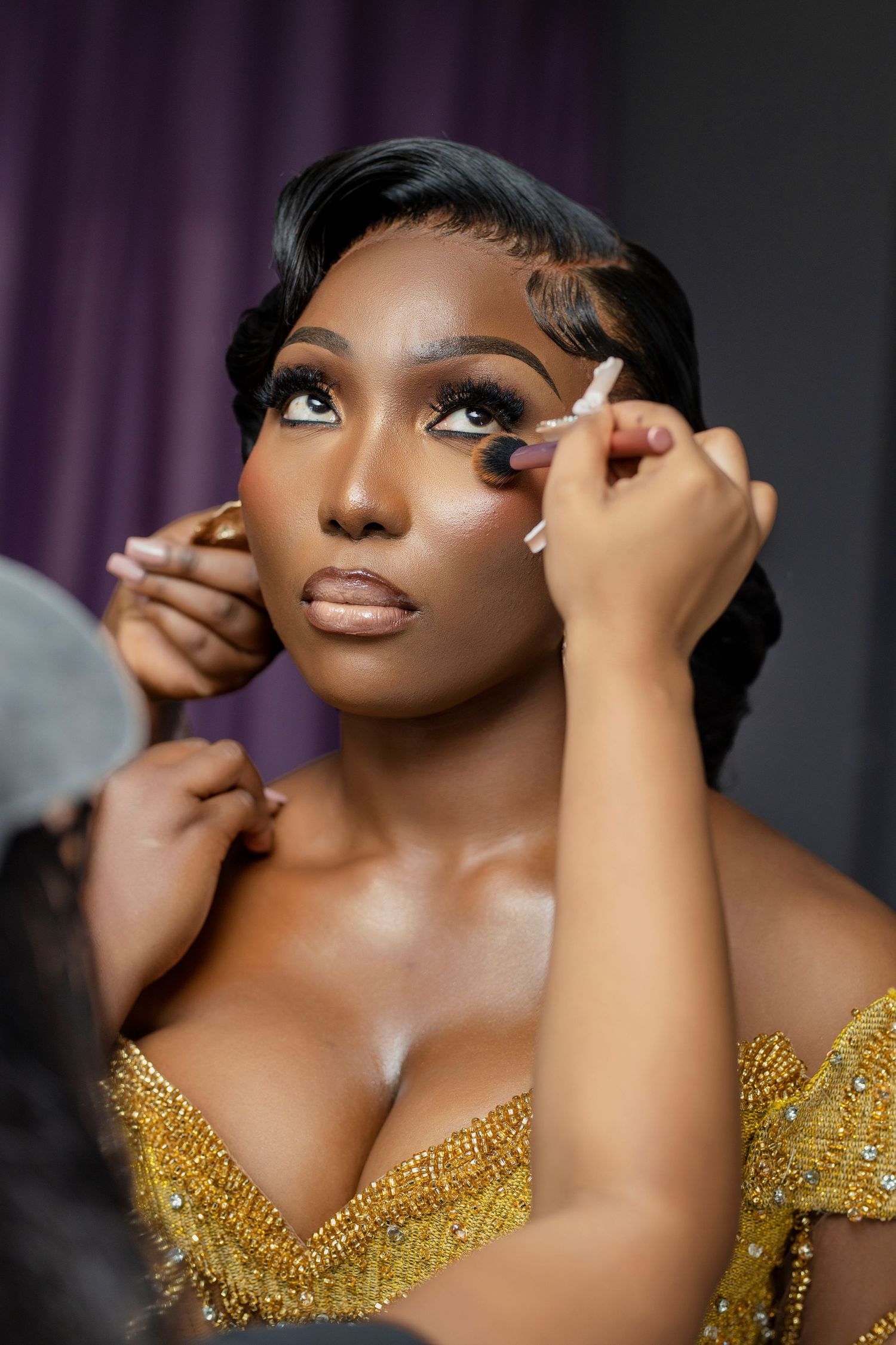 Close-up beauty shot showing glamorous makeup application with gold sequined bodice.