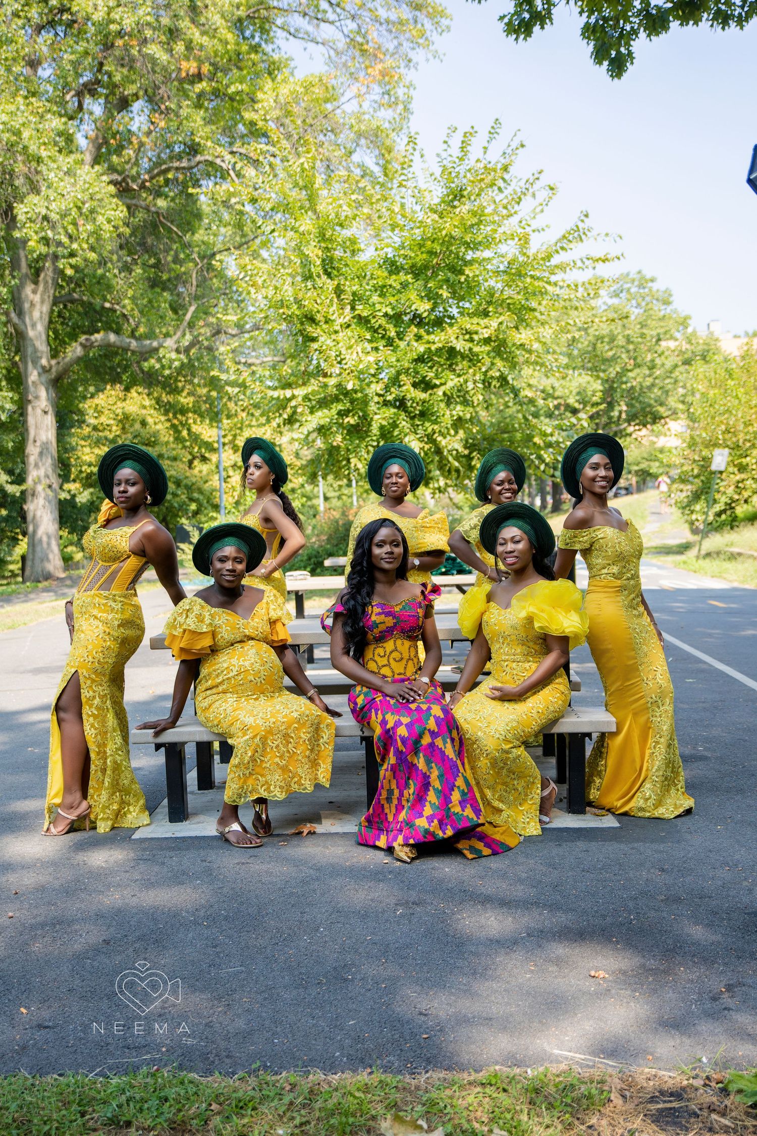 A group wearing matching yellow dresses poses together on a wooden bench outdoors.