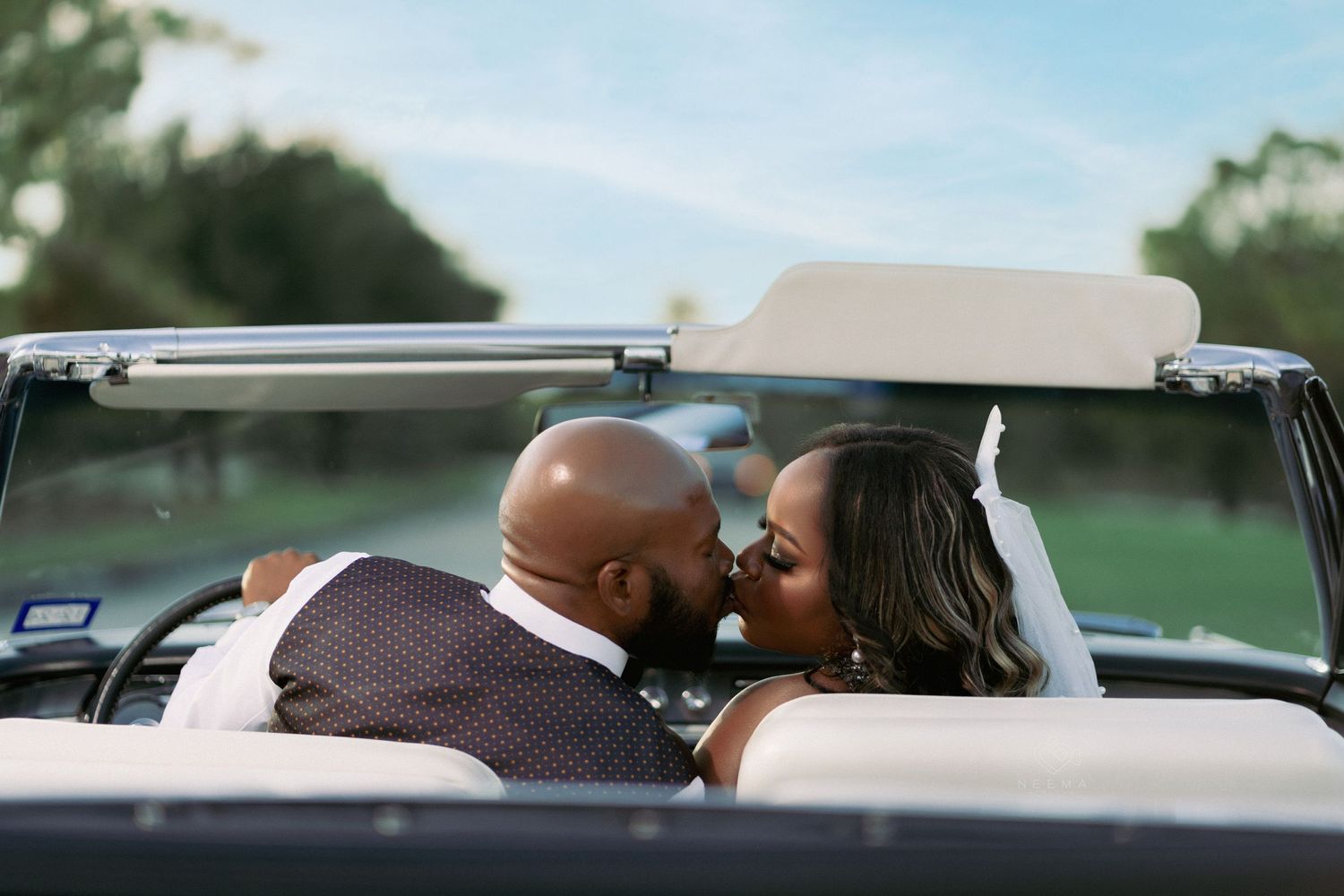 Newlywed couple sharing romantic moment in vintage convertible car.