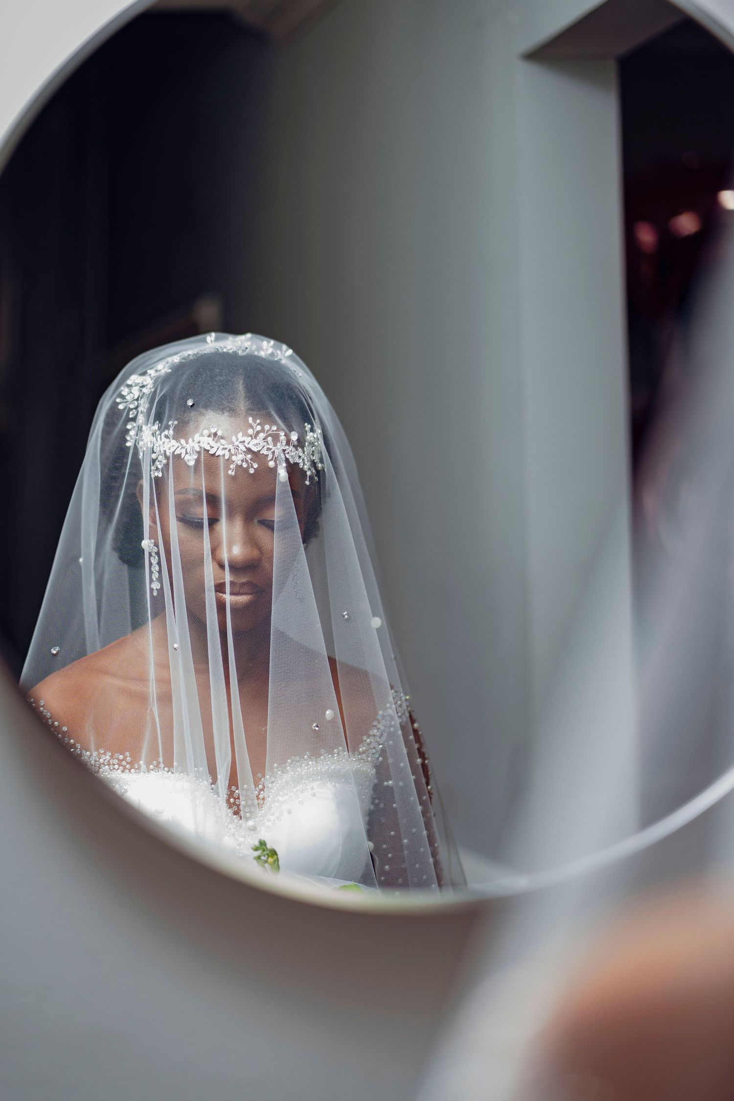 Artistic mirror reflection of bride wearing delicate veil and crystal headpiece.