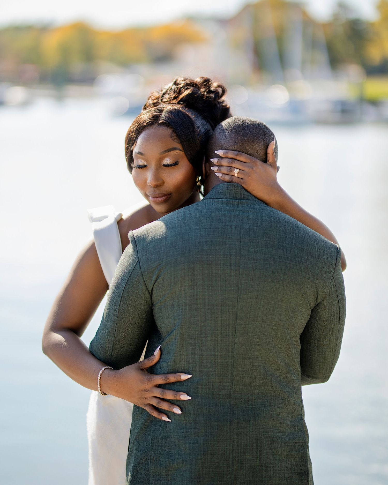 Romantic outdoor wedding photo capturing intimate embrace by marina at sunset.