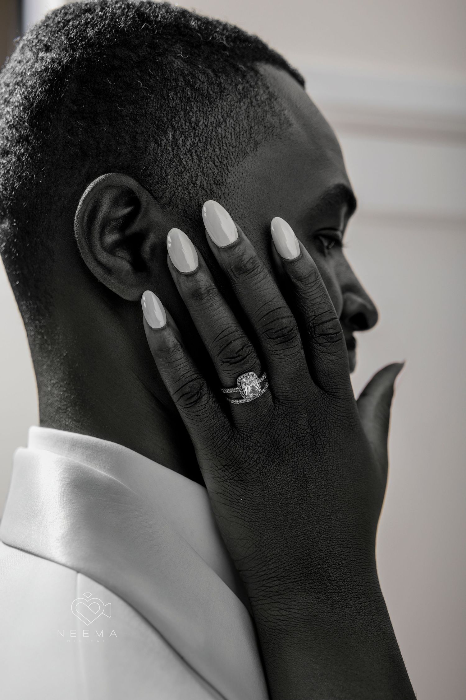 Close up profile view showing white painted nails and diamond engagement ring.