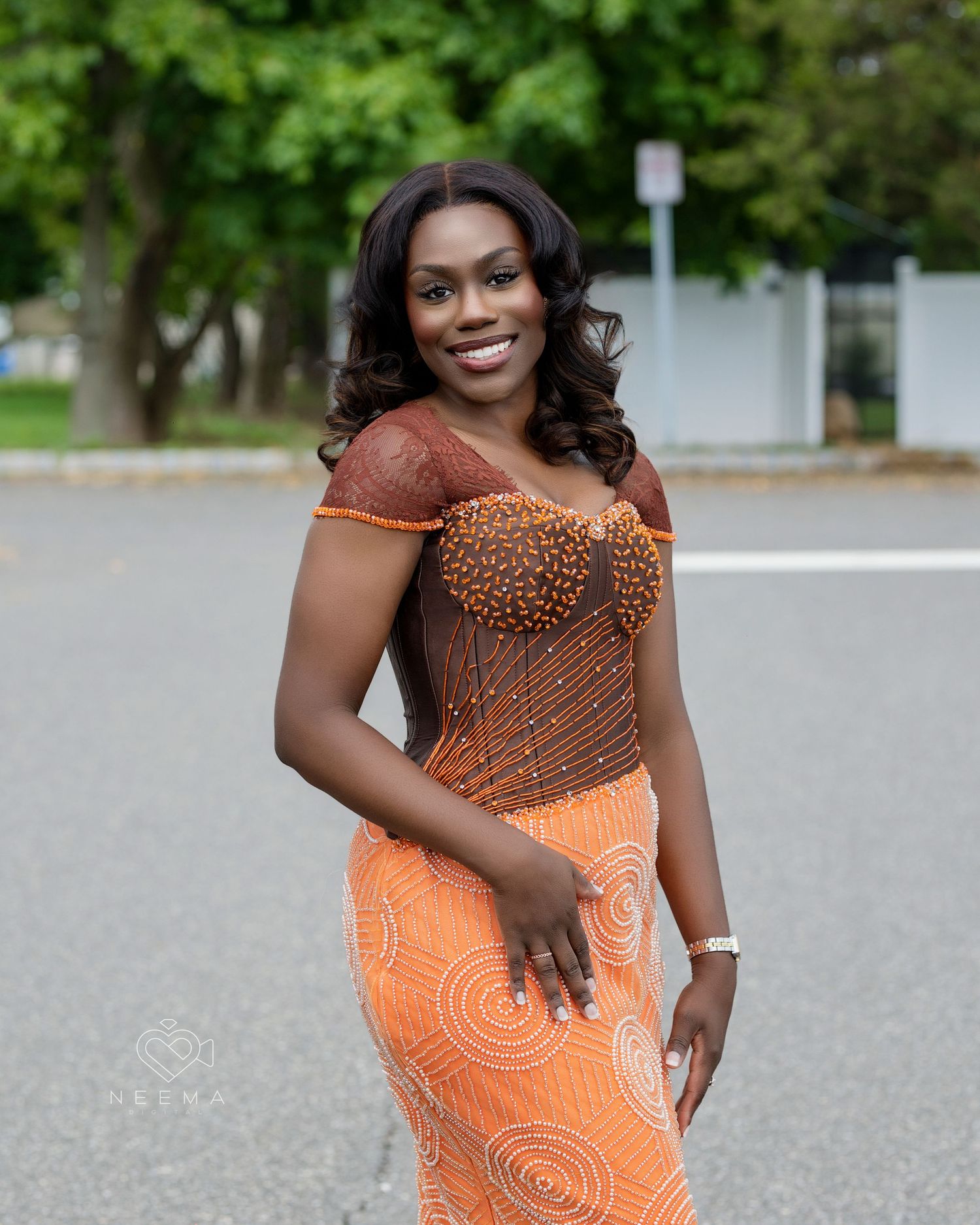 Person in fitted orange beaded dress poses outdoors.