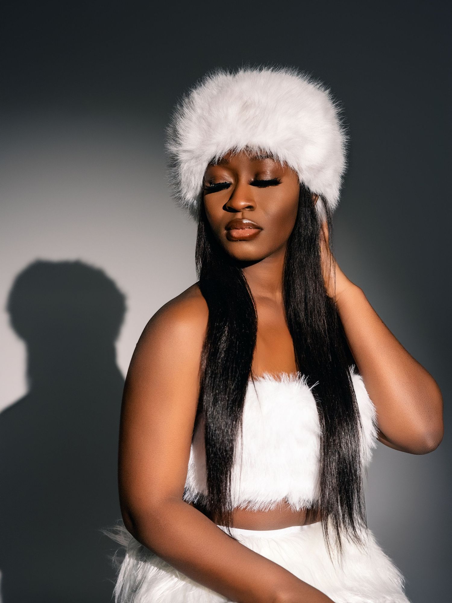 An artistic portrait featuring white winter fashion accessories against a dark background.