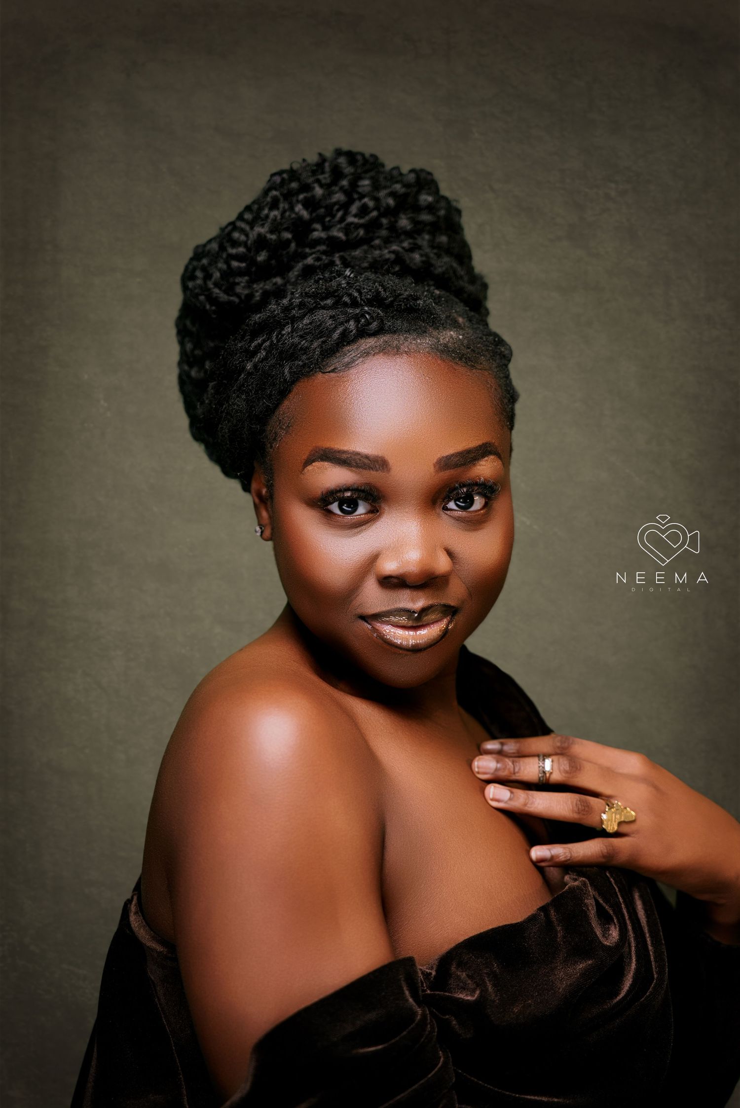 Glamour portrait with dramatic lighting featuring elegant off-shoulder black dress and updo hairstyle.