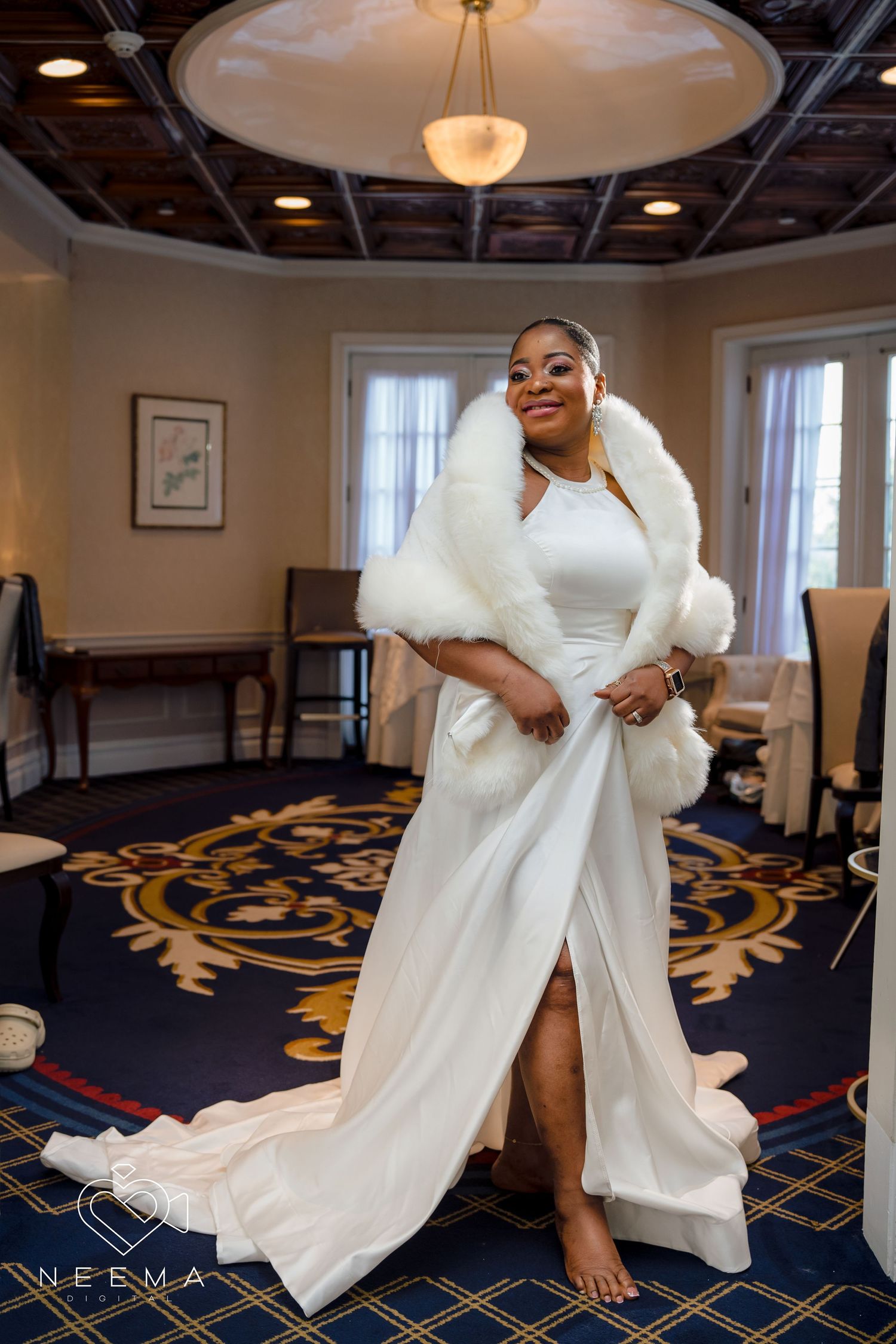 Elegant white wedding gown with fur wrap photographed in luxurious hotel interior.