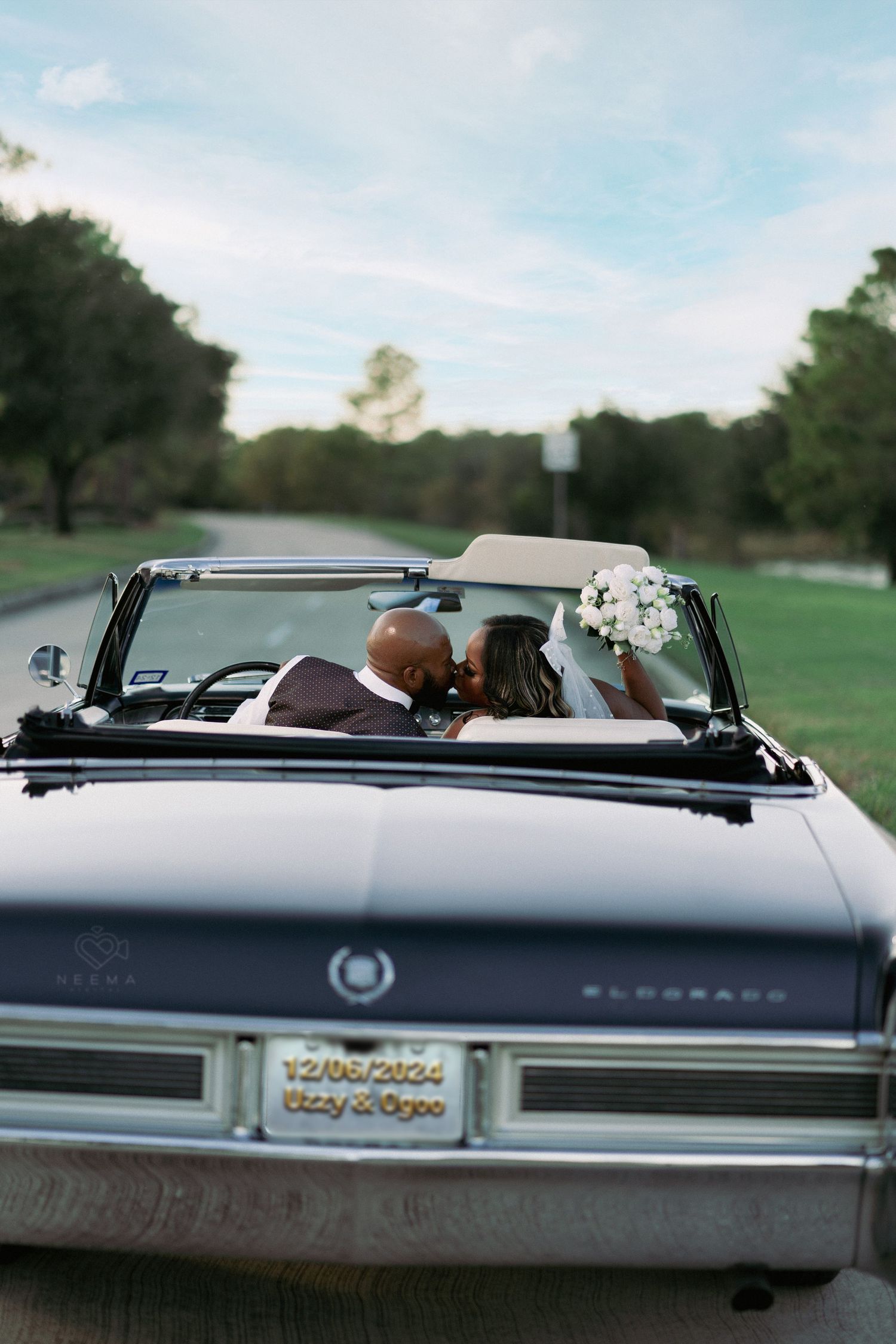Back view of couple in vintage Eldorado convertible on scenic drive.