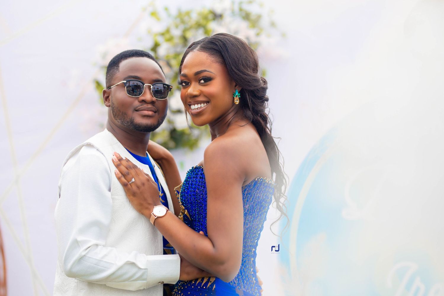A couple embraces while wearing formal attire at an outdoor celebration.
