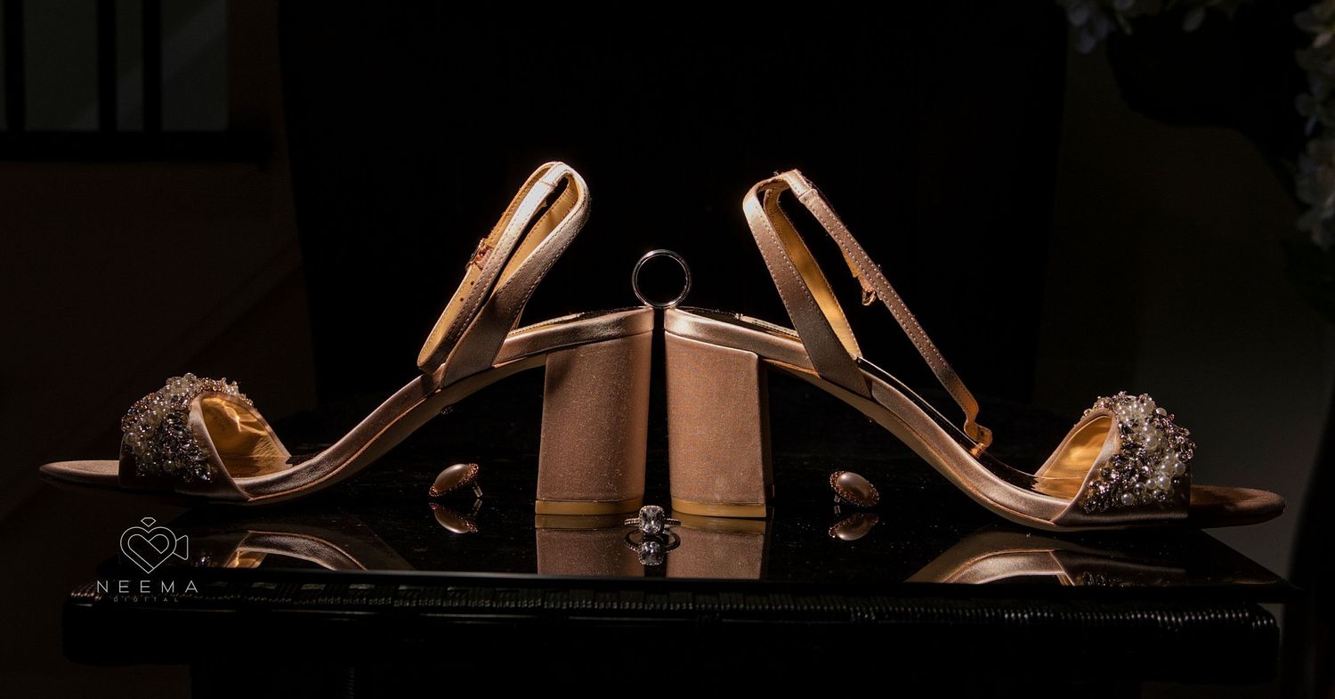 Elegant gold high heel shoes displayed artistically against dark background.