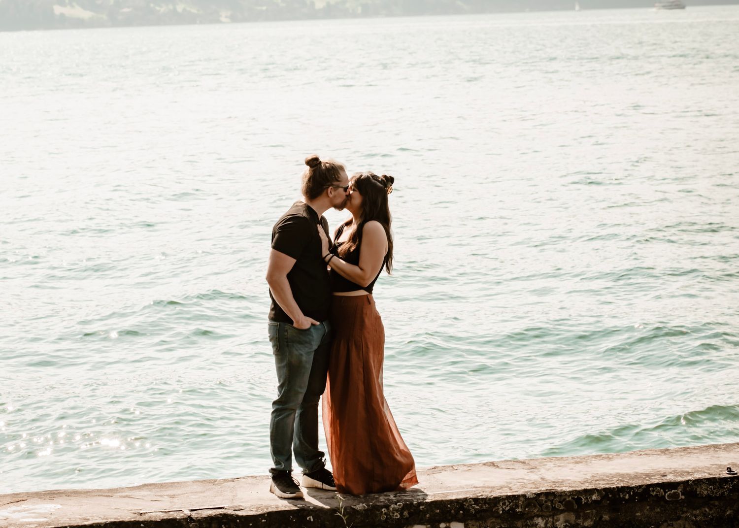 Emily Hall and husband share an intimate moment while standing on a rock wall at Meggenhorn Castle in Luzern, Switzerland