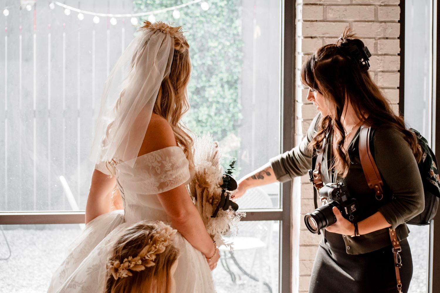 Emily Hall, wedding photographer taking pictures of bride in white dress and veil near window at The Little Cottage in Smyrna, Georgia.