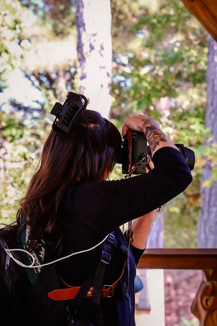 Emily Hall, Wedding Photographer, taking photos through a  in an outdoor setting at Koury Farms in Auburn, Georgia