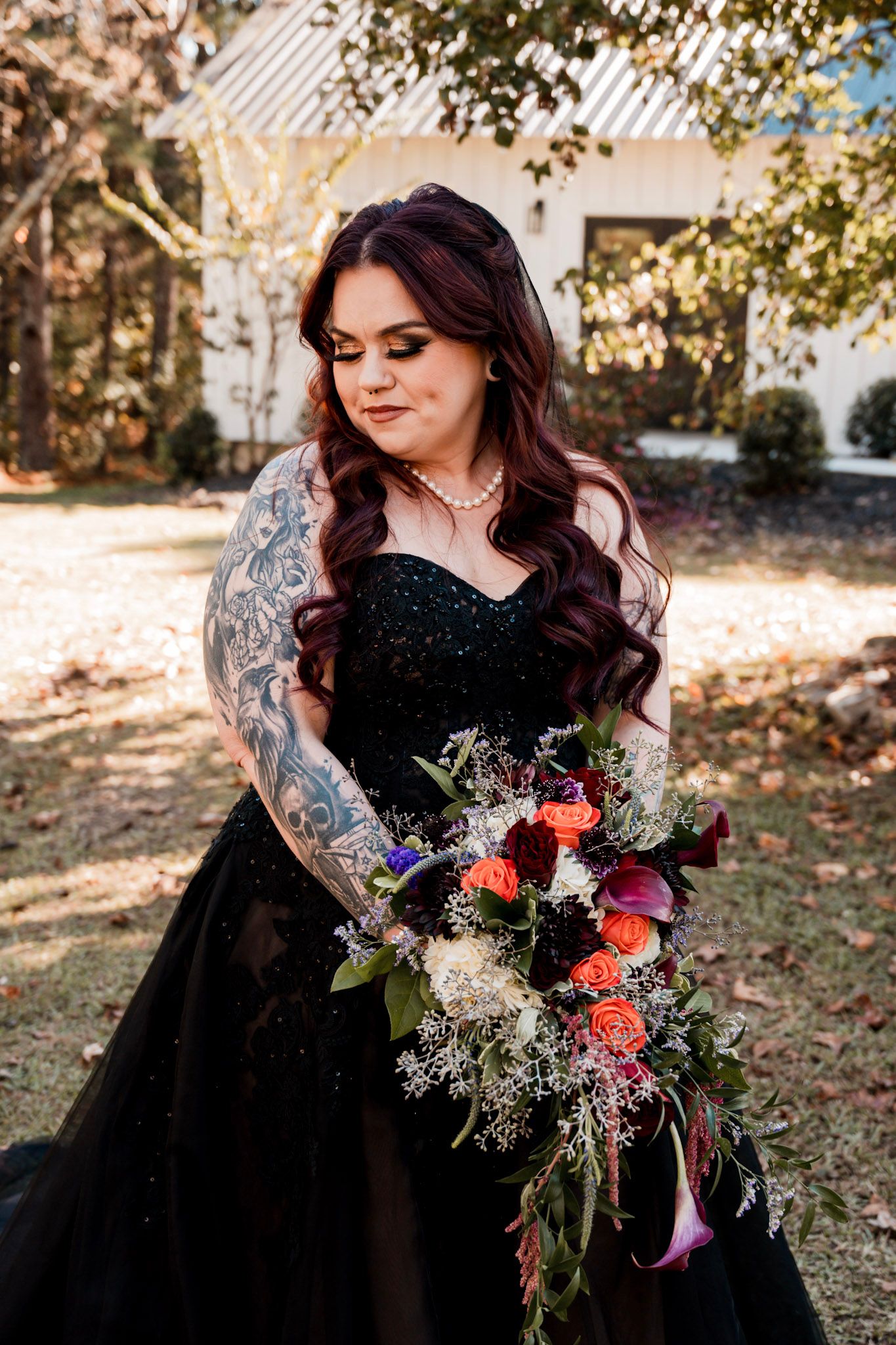 A bouquet  is held against a black dress in an outdoor autumn setting by a bride at Koury Farms in Auburn, Georgia.