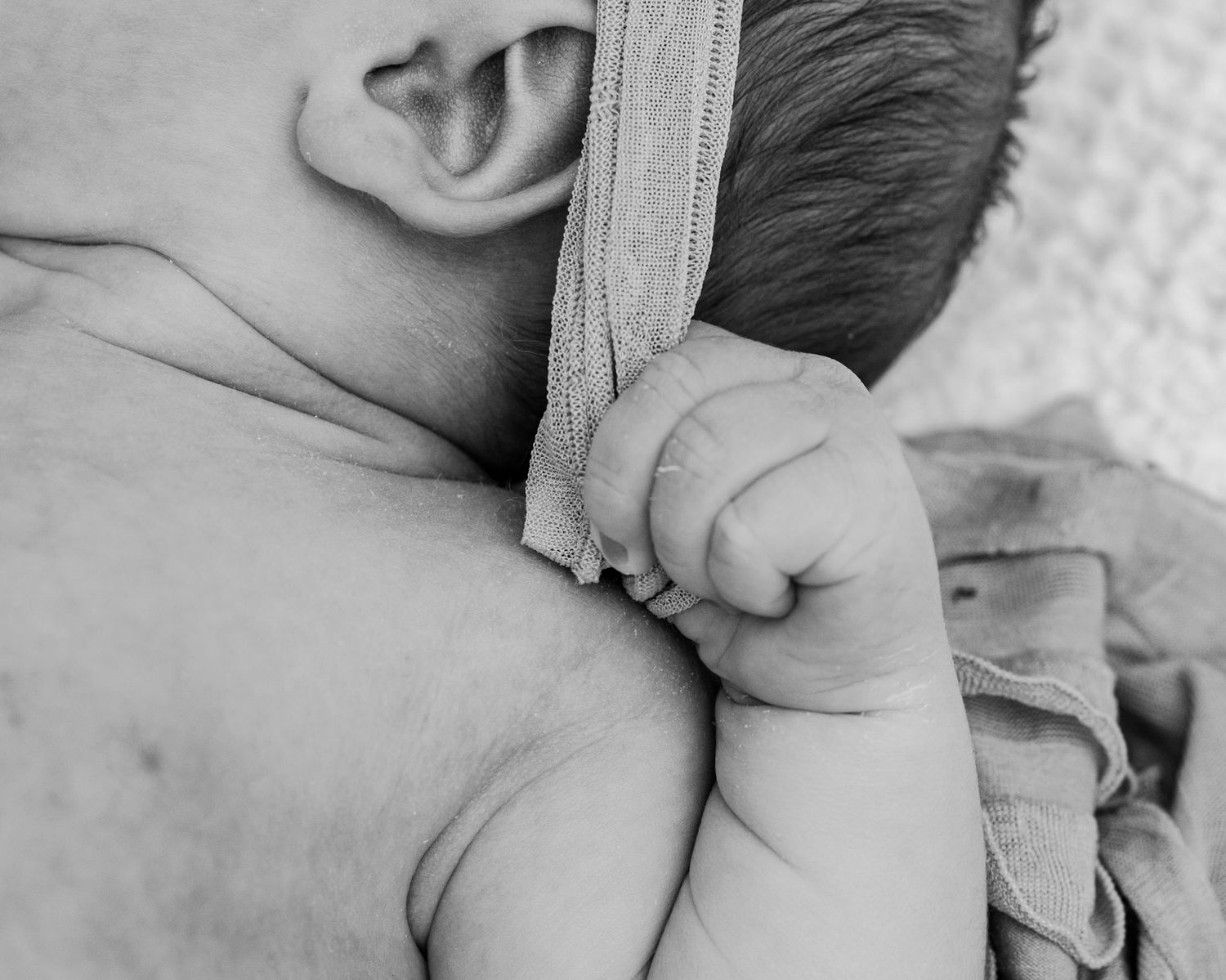 A black and white close-up photo showing hands and head of a newborn baby in Covington, Georgia