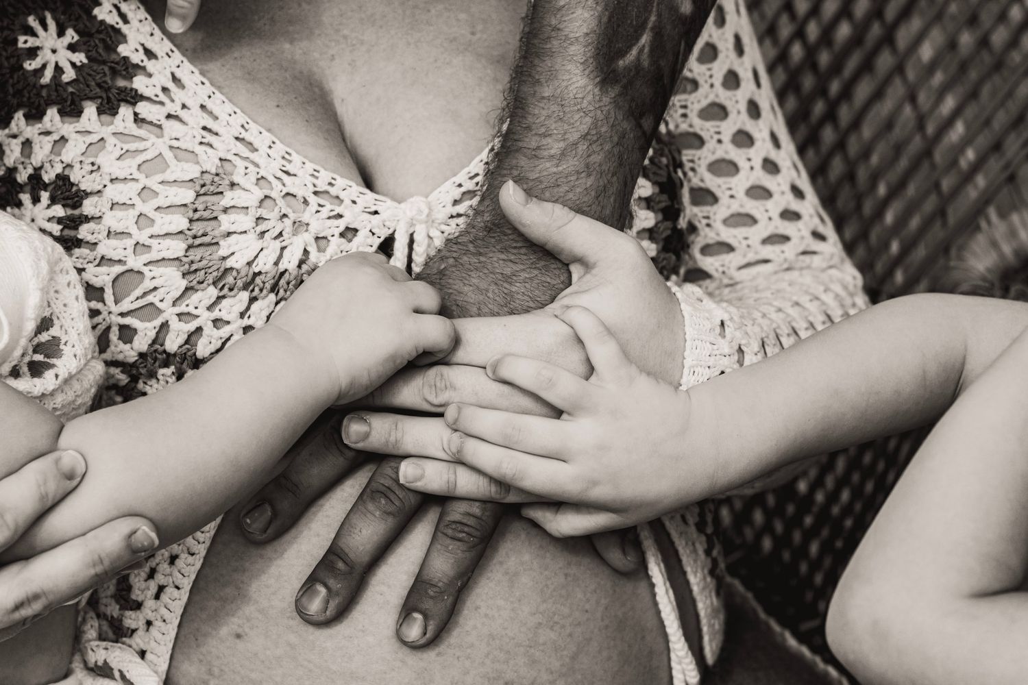 Black and white photo collage showing hands cradling a newborn baby wrapped in a polka dot blanket.
