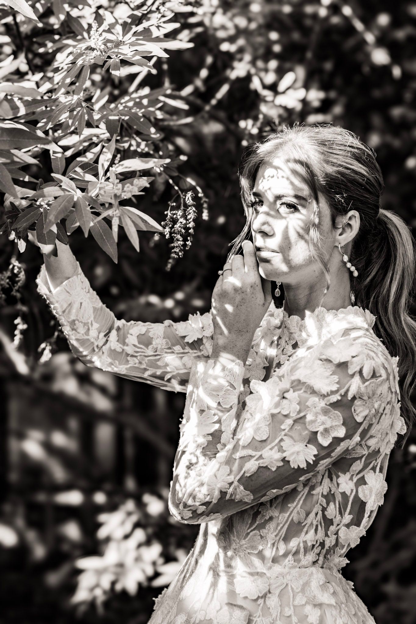 A bride in a lace dress stands in a garden in black and white portrait at The Wildflower 301  wedding venue in Greensboro, Georgia