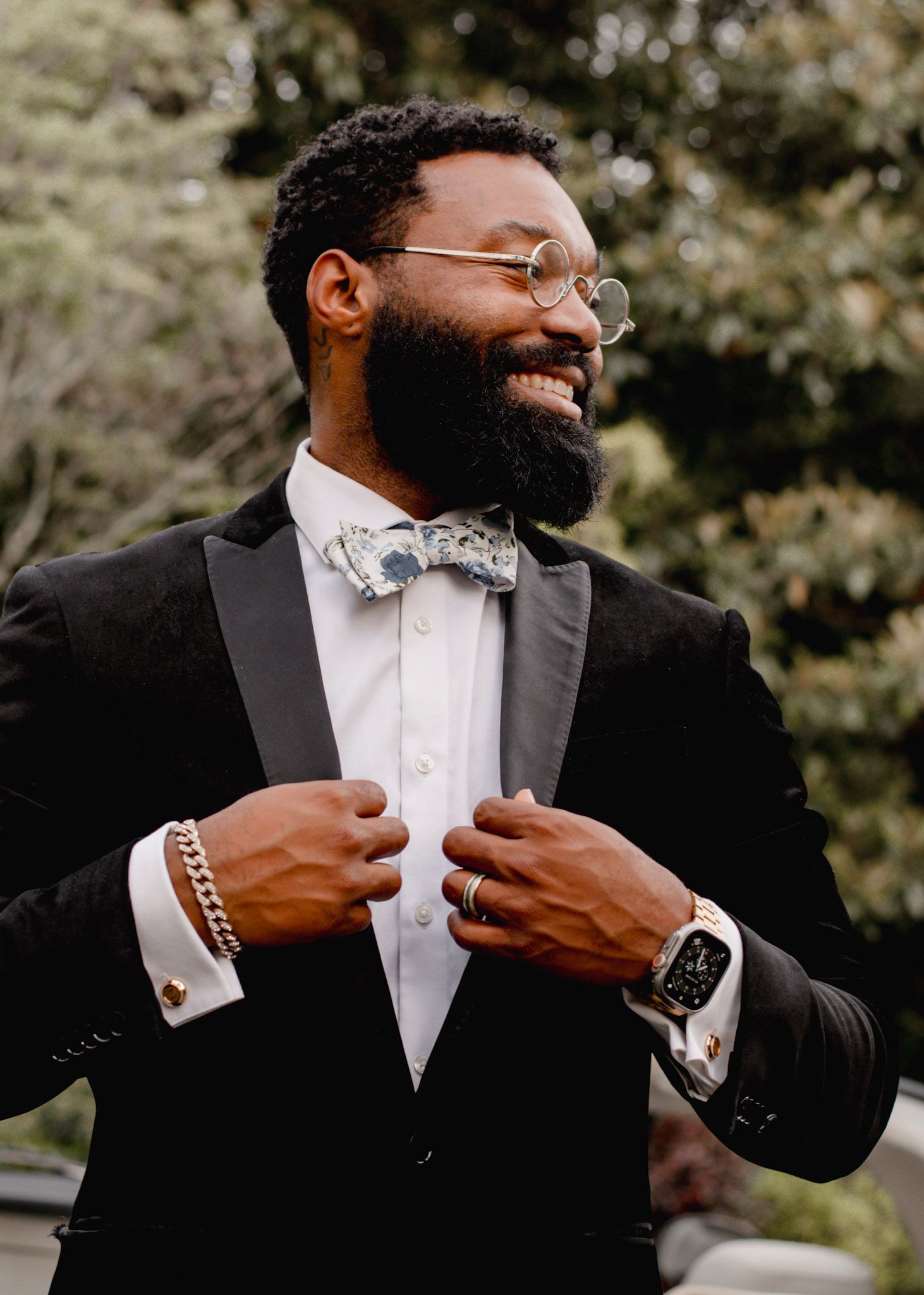 A groom in a black tuxedo and white bow tie laughs joyfully during a wedding photoshoot  Wildflower 301 Venue in Greensboro, Georgia