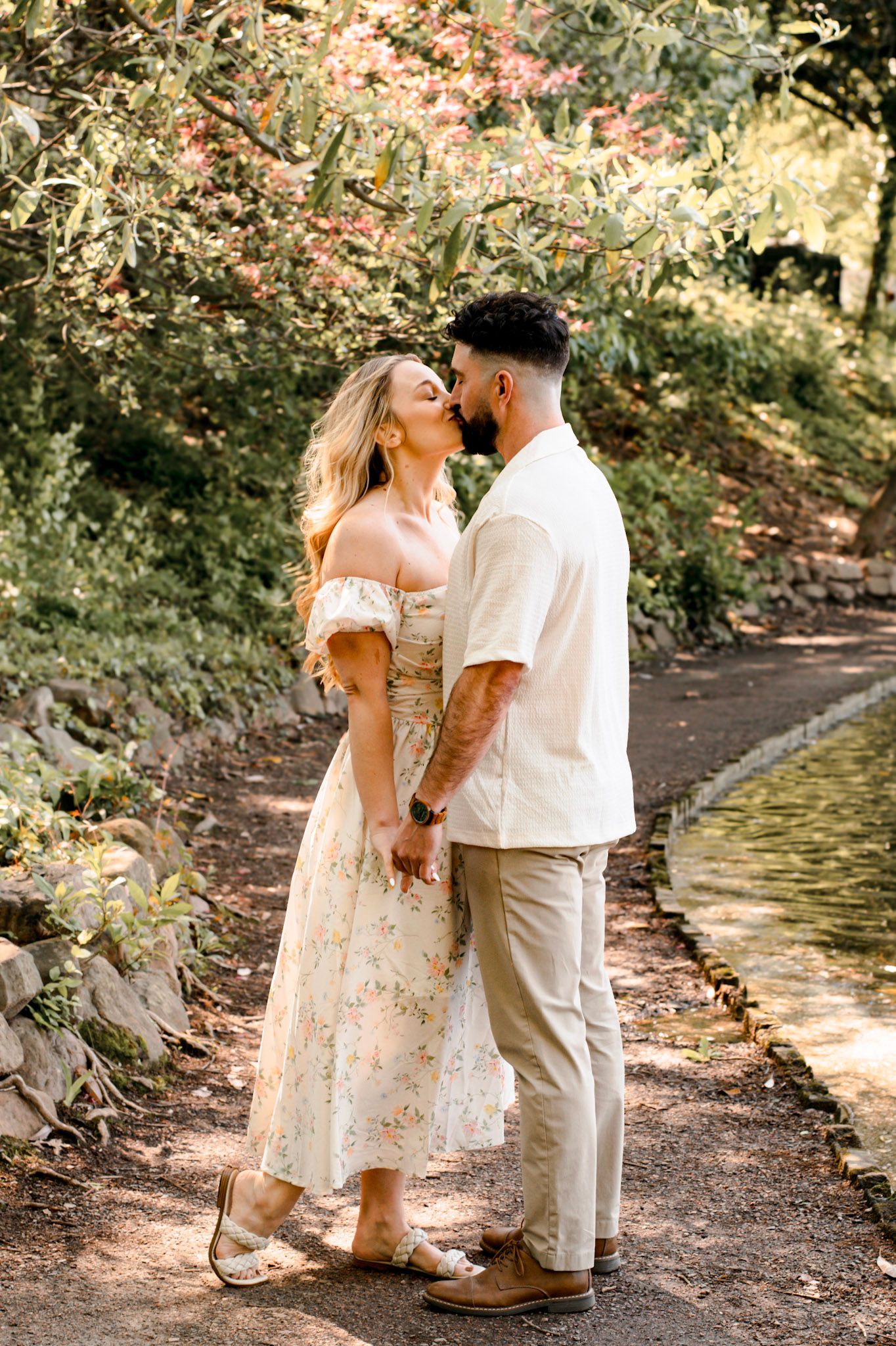 A romantic couple shares engagement session along a wooded path at Piedmont park in warm sunlit nature setting in Atlanta, Georgia