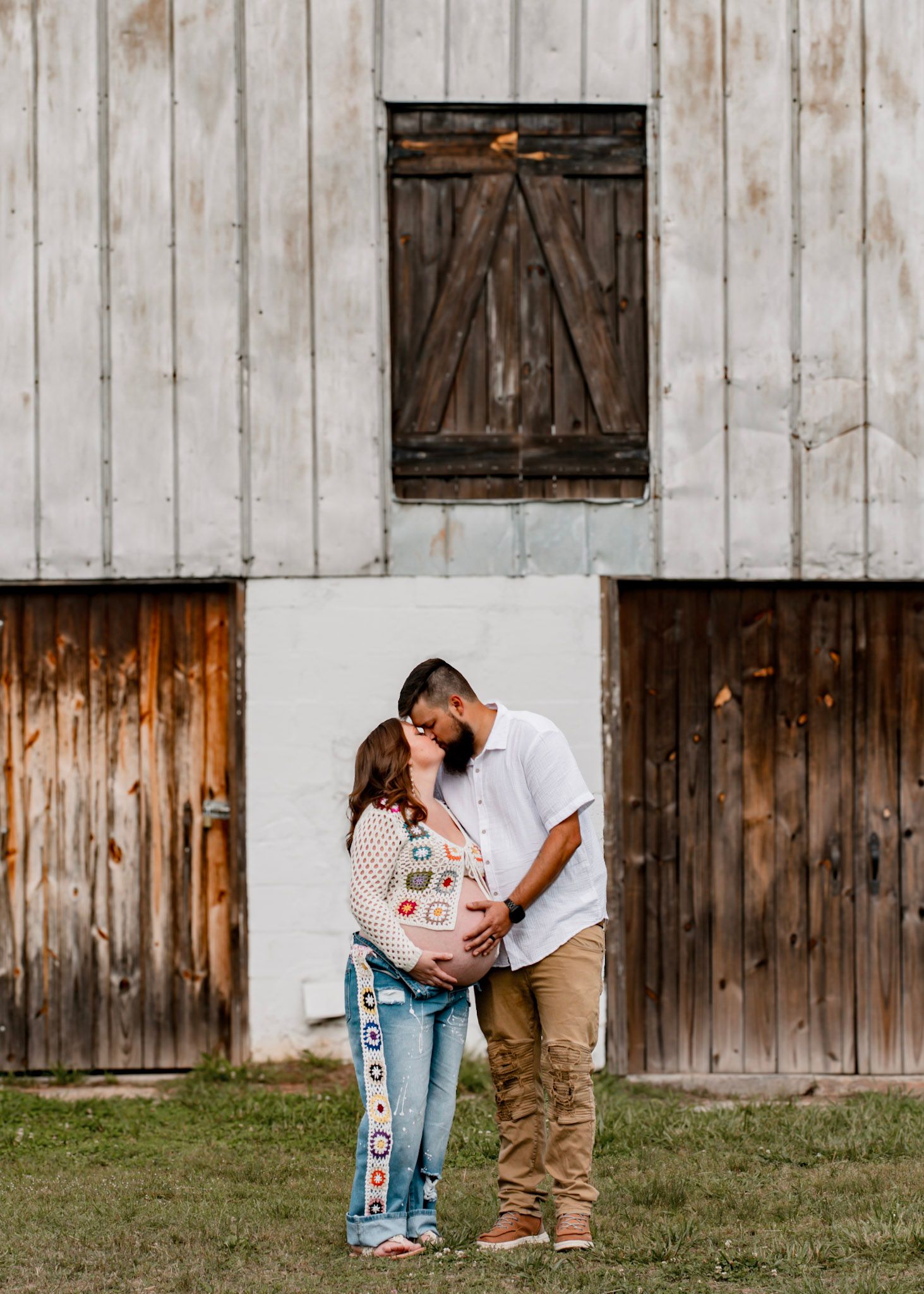 A romantic couple embraces against a rustic barn maternity session at Vaughter's Farm in Lithonia, Georgia.